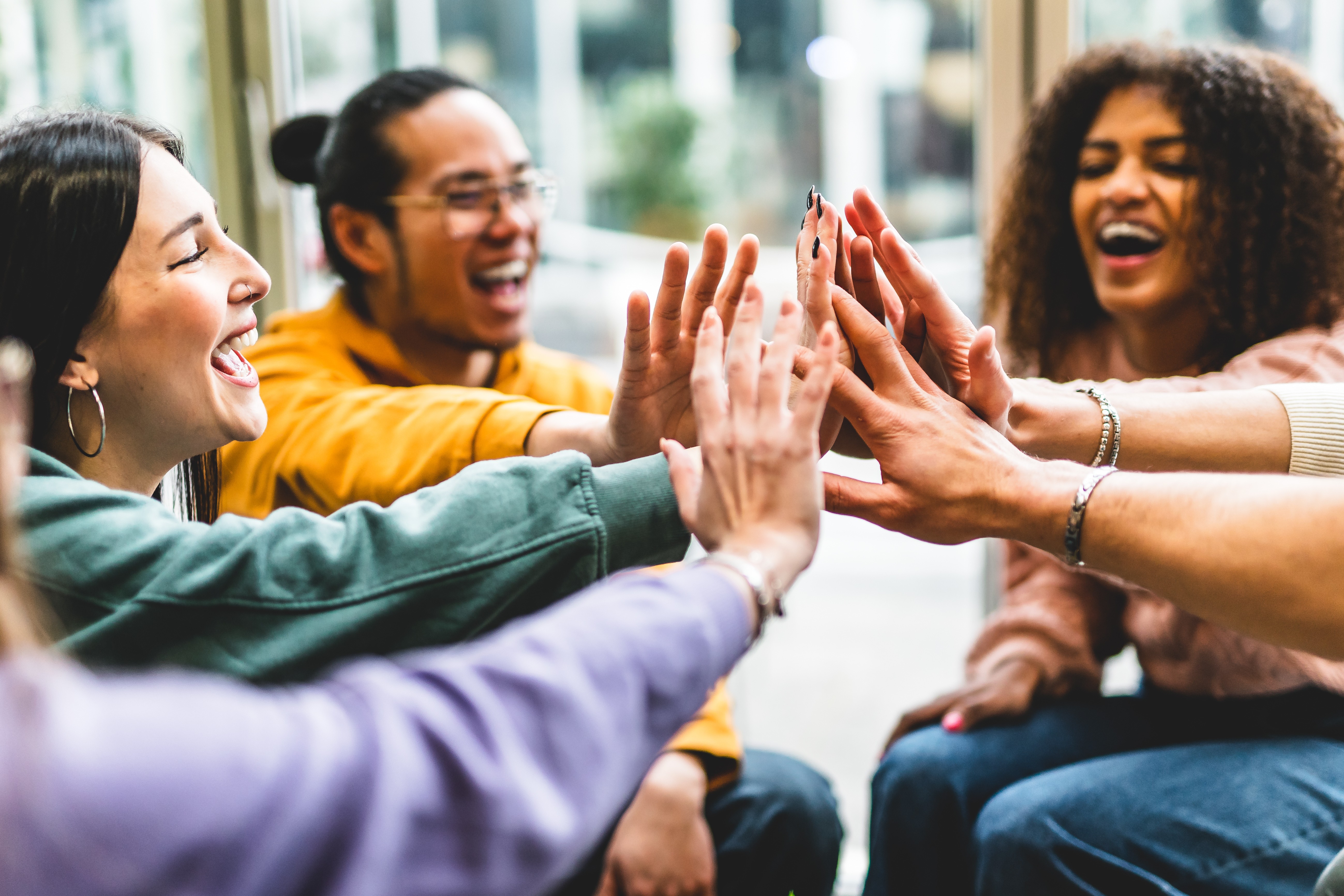 Group of students smiling and high-fiving in a collaborative campus setting