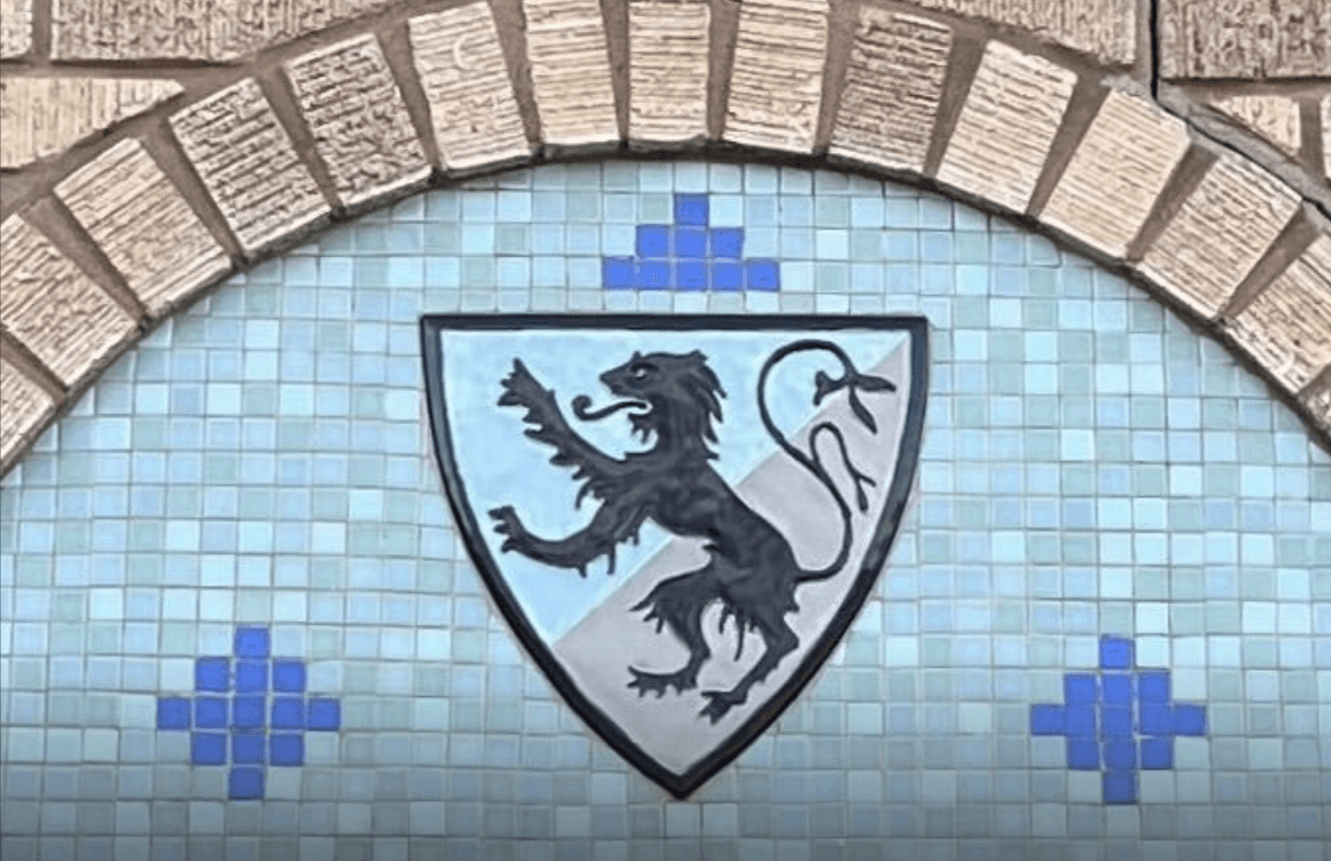 A closeup of a tile mosaic with a large central tile with a lion standing on two feet. The lion's tail is forked