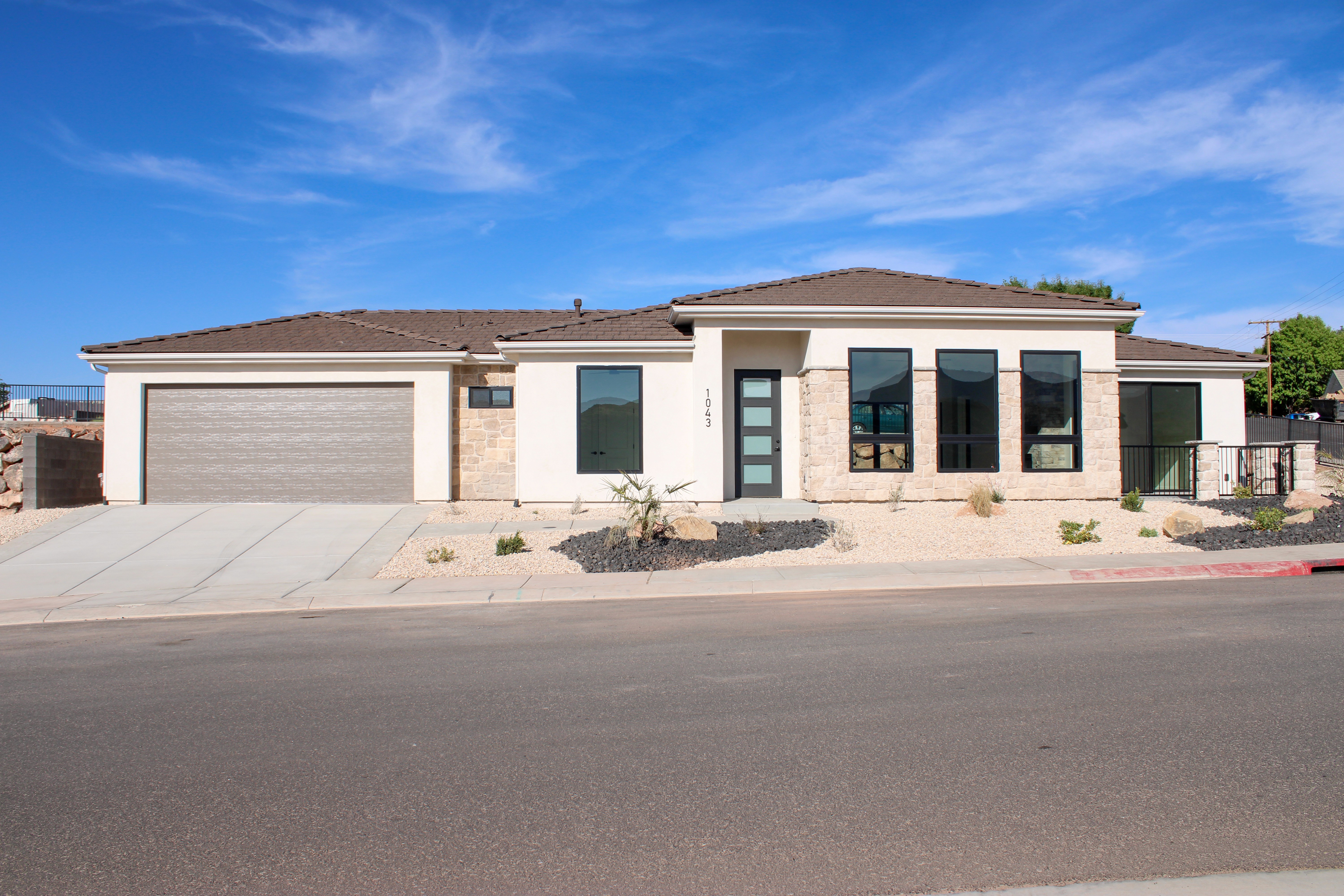 Front exterior of The Overlook at Falcon Ridge in Hurricane, Utah, showing stone and stucco façade, entryway, and landscaping in daylight.