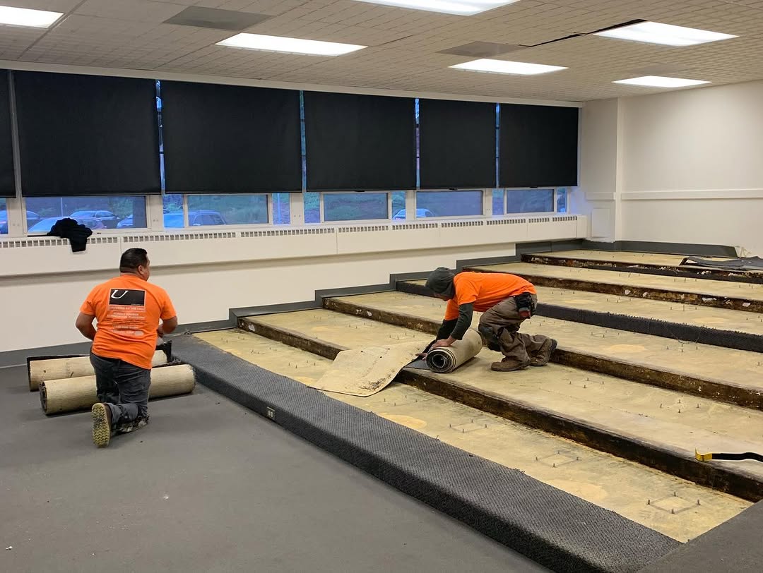 Installers stripping carpet from conference room risers down to the plywood