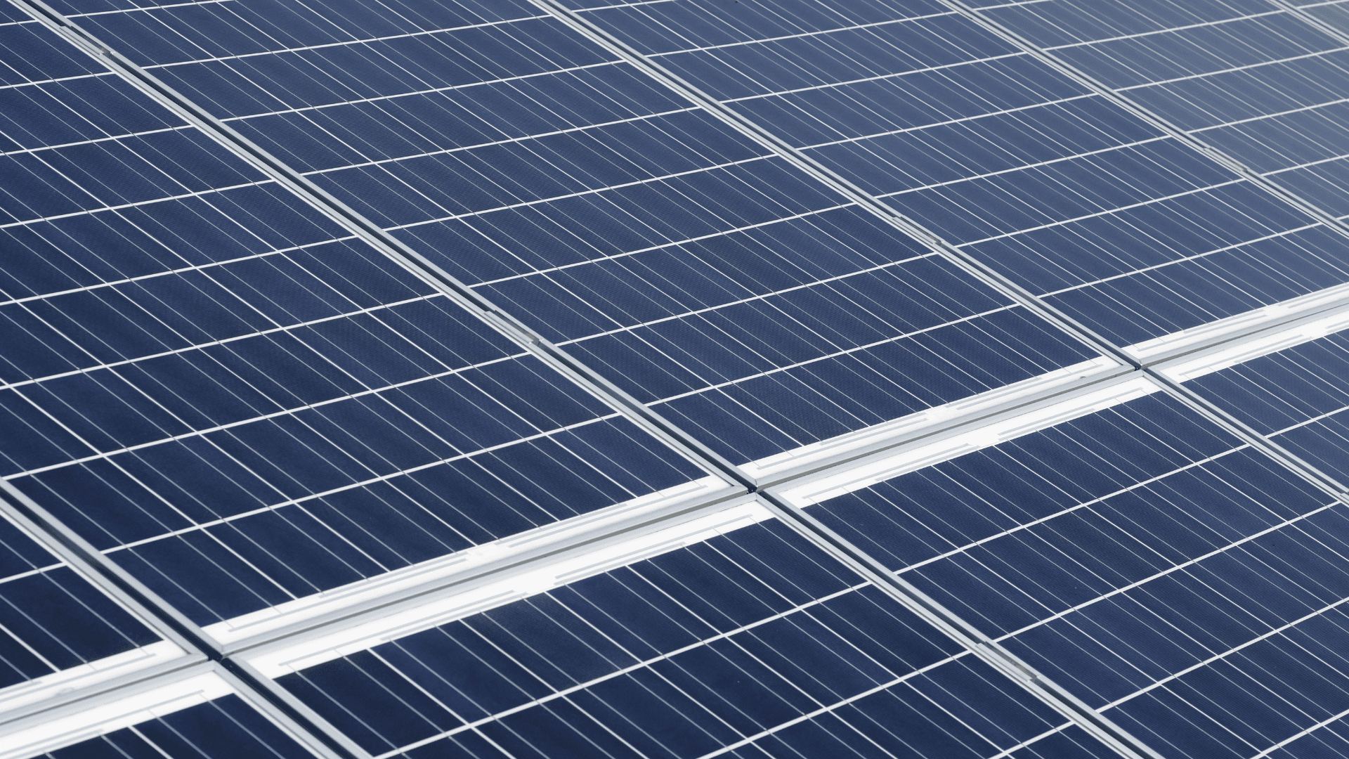 Nahaufnahme von Solarpaneelen, die dunkelblaue photovoltaische Zellen mit einem weißen Rastermuster zeigen.