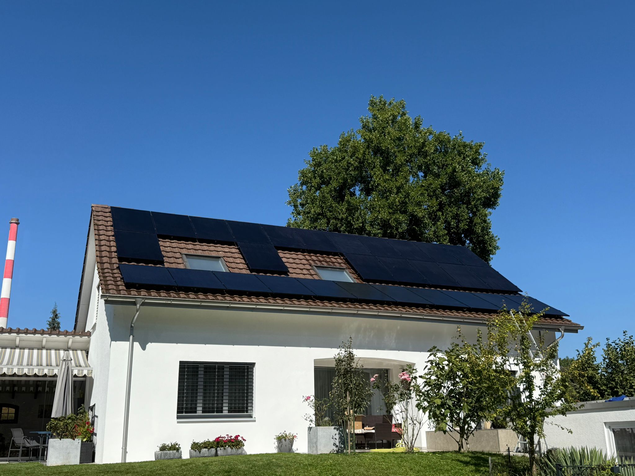 Moderne Hausfassade in Wildegg mit einer leistungsstarken 19 kWh Photovoltaikanlage unter blauem Himmel.