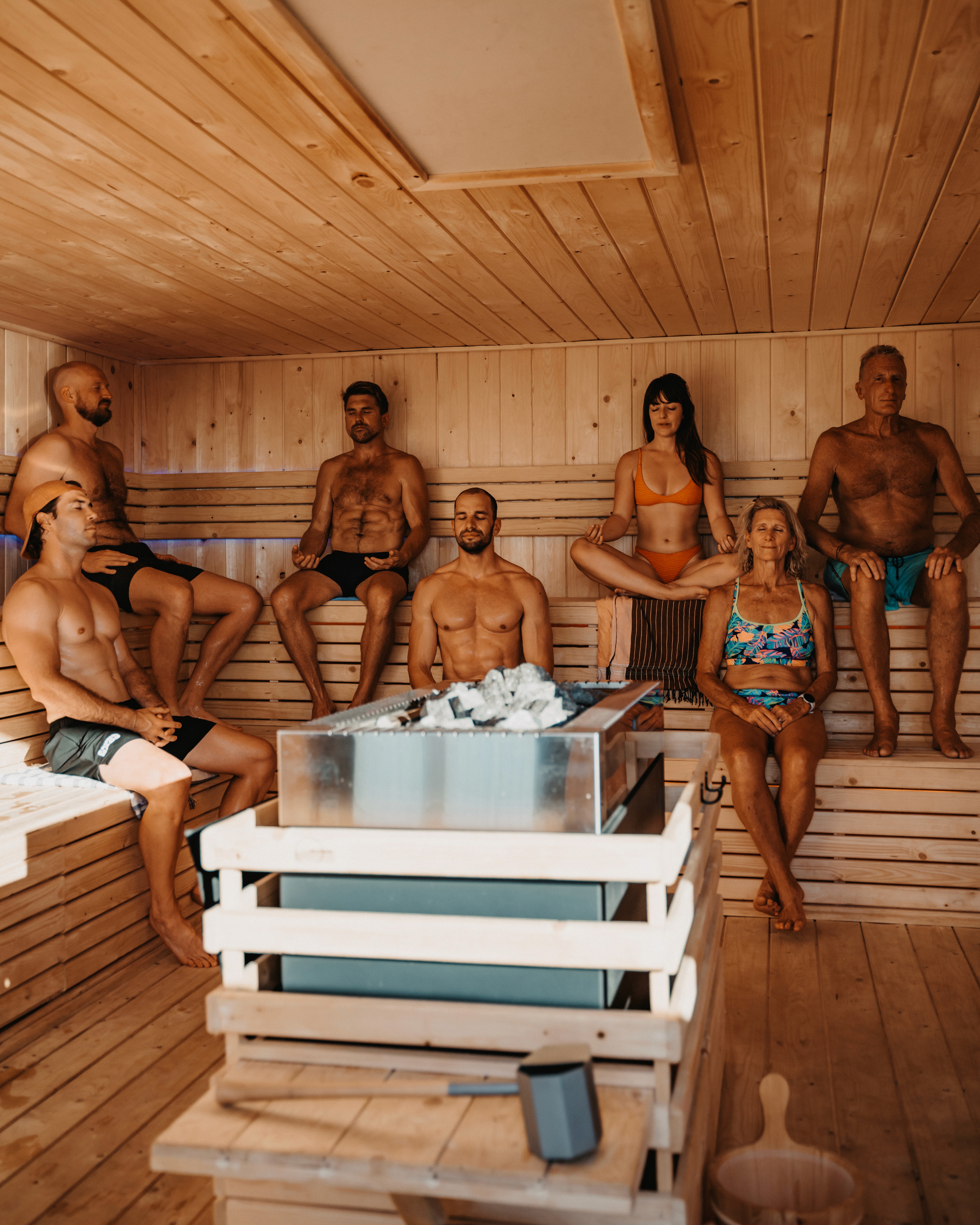 Group of guests sitting inside the wooden sauna at SaunaHaüs Cape Town during a guided heat session.