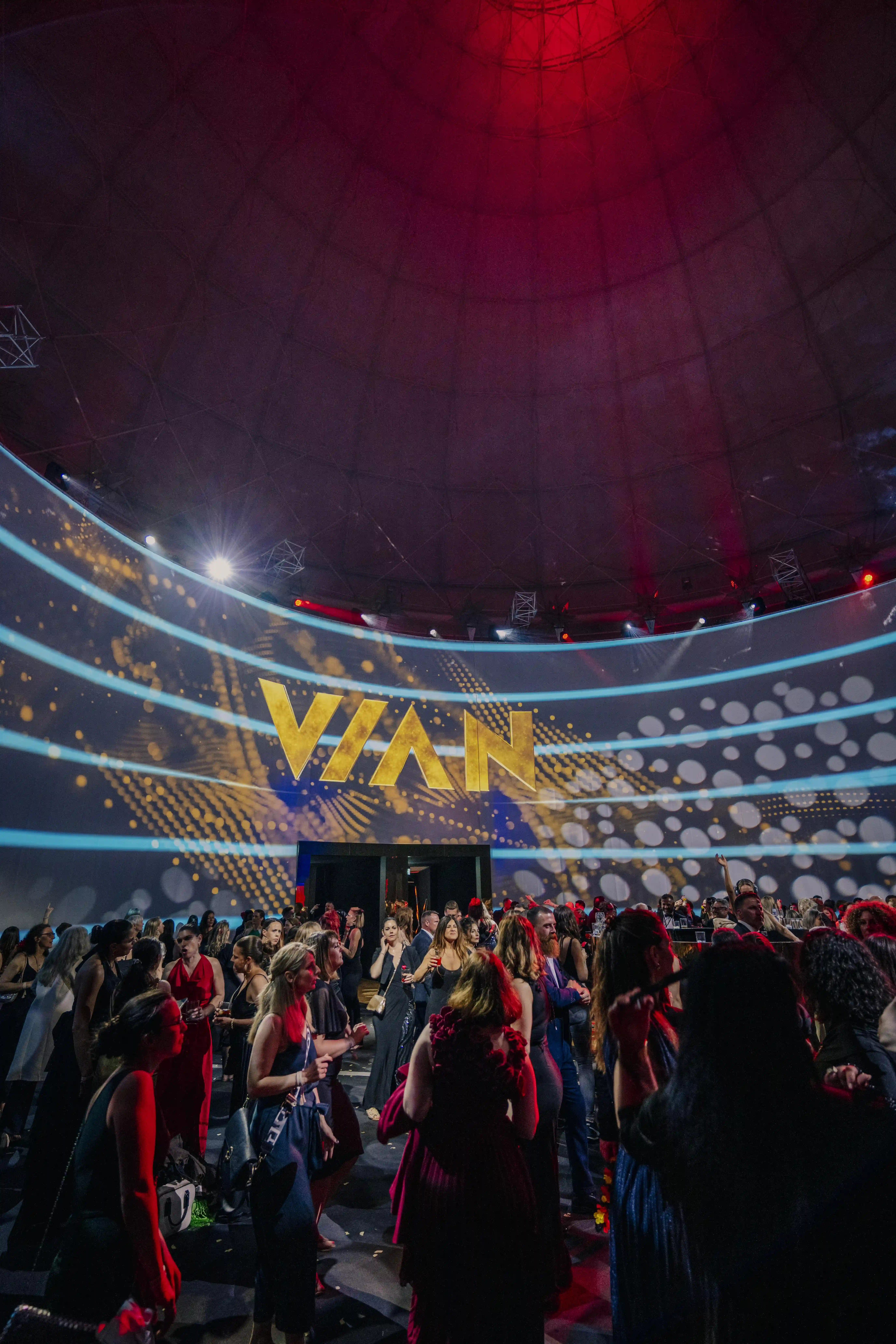 Dancing guests under the red-lit dome with curved Vian LED wall.