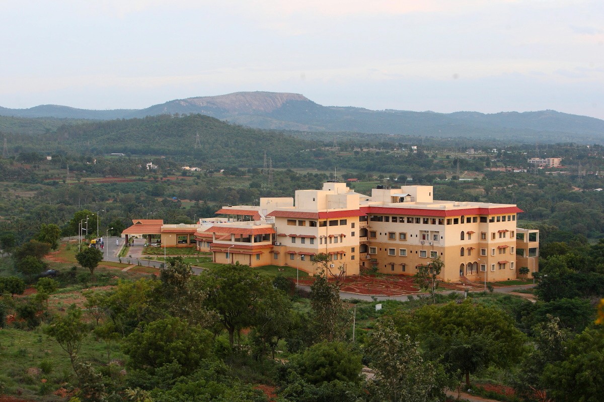 Aerial view of a winding road cutting through rocky terrain and sandy landscape.