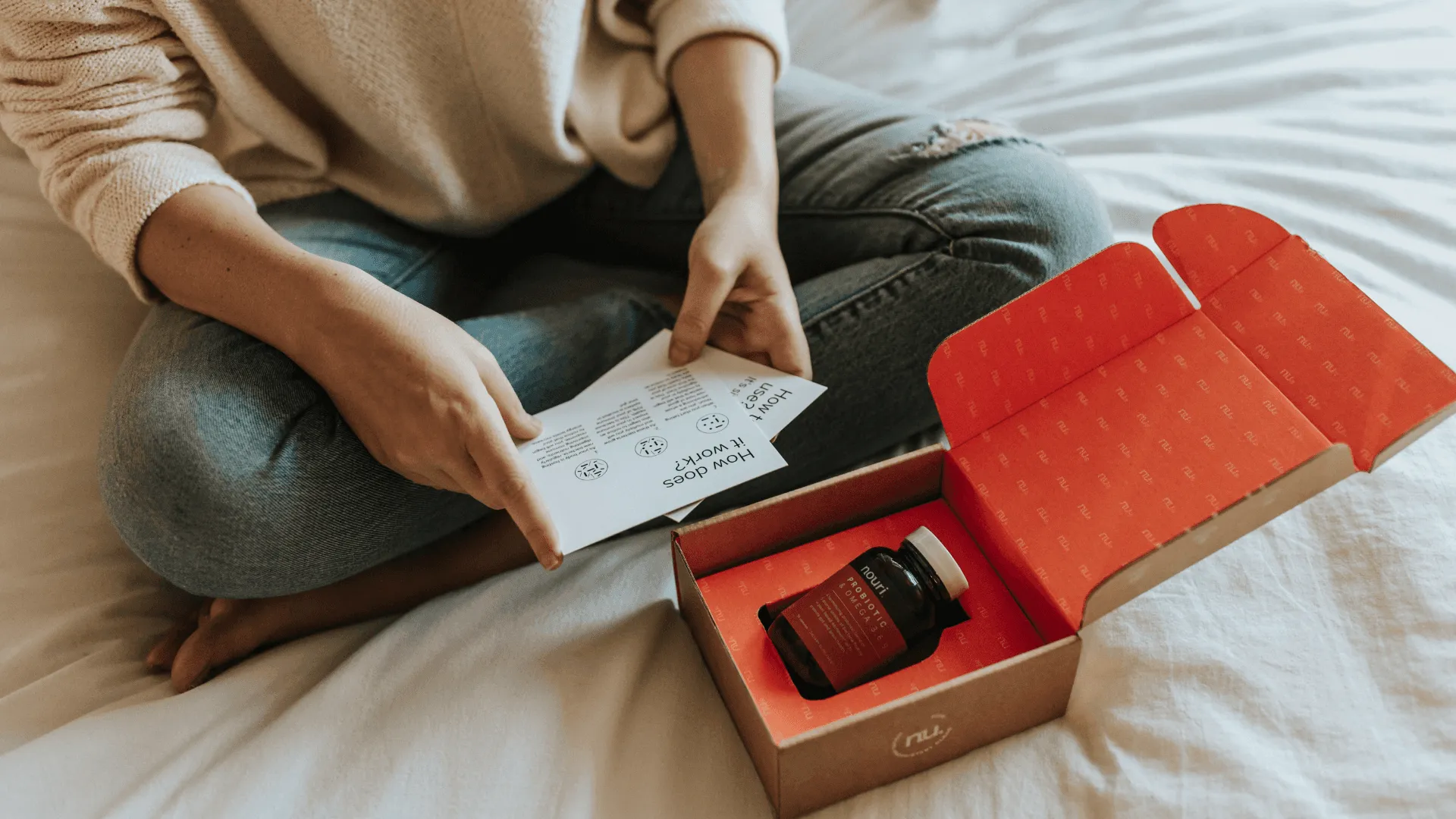 Someone sitting on a bed unboxing something they've just purchased online