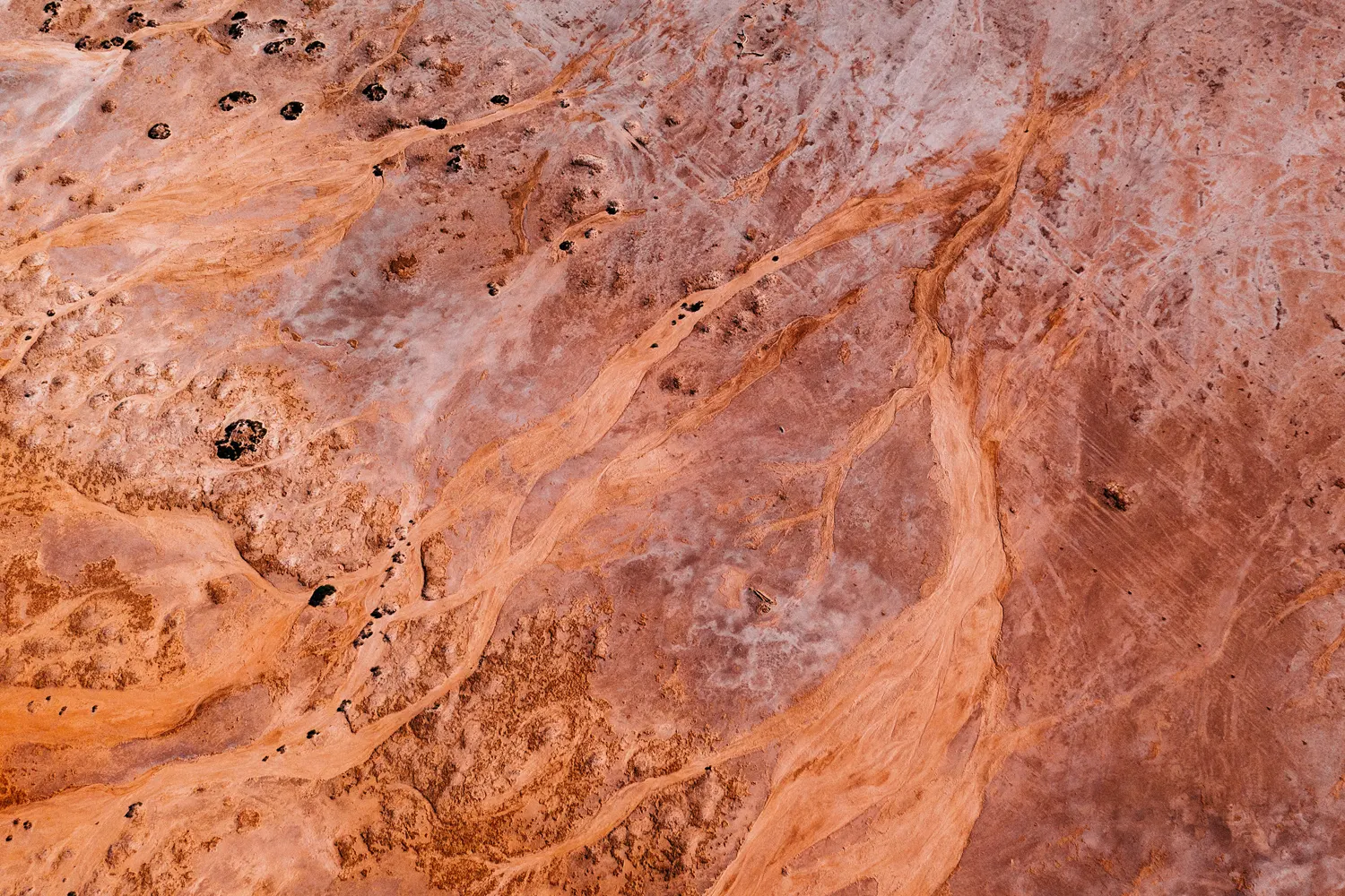 Aerial looking down on eroded orange rock and sand patterning