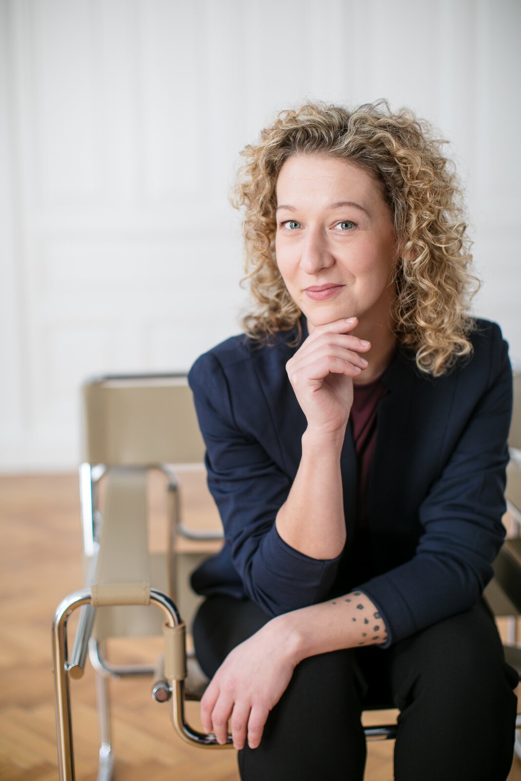 Portrait von Sandra Kitting, empathische UI/UX-Designerin aus Wien, sitzend mit nachdenklicher Pose in hellem Innenraum und mit freundlichem Ausdruck