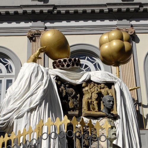 פסלים מזהב ופירוטים מעוטרים על חזית בניין, הכוללים דמויות לבנות עטויות ופיסולים מורכבים.