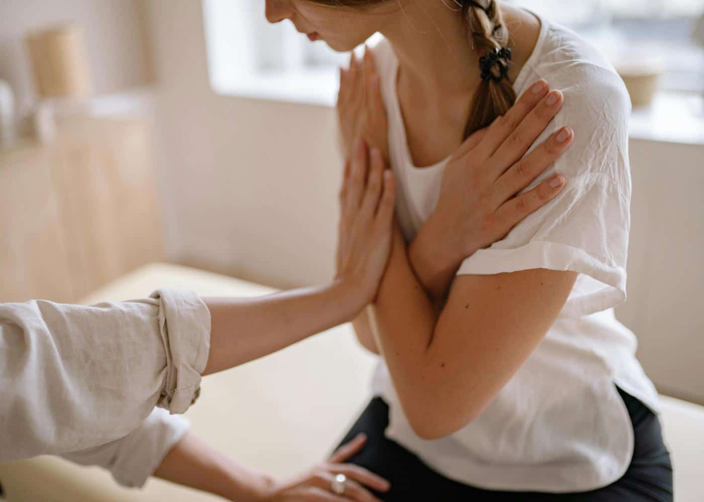 Young woman with her arms crossed while doctor guides her through posture correction exercies