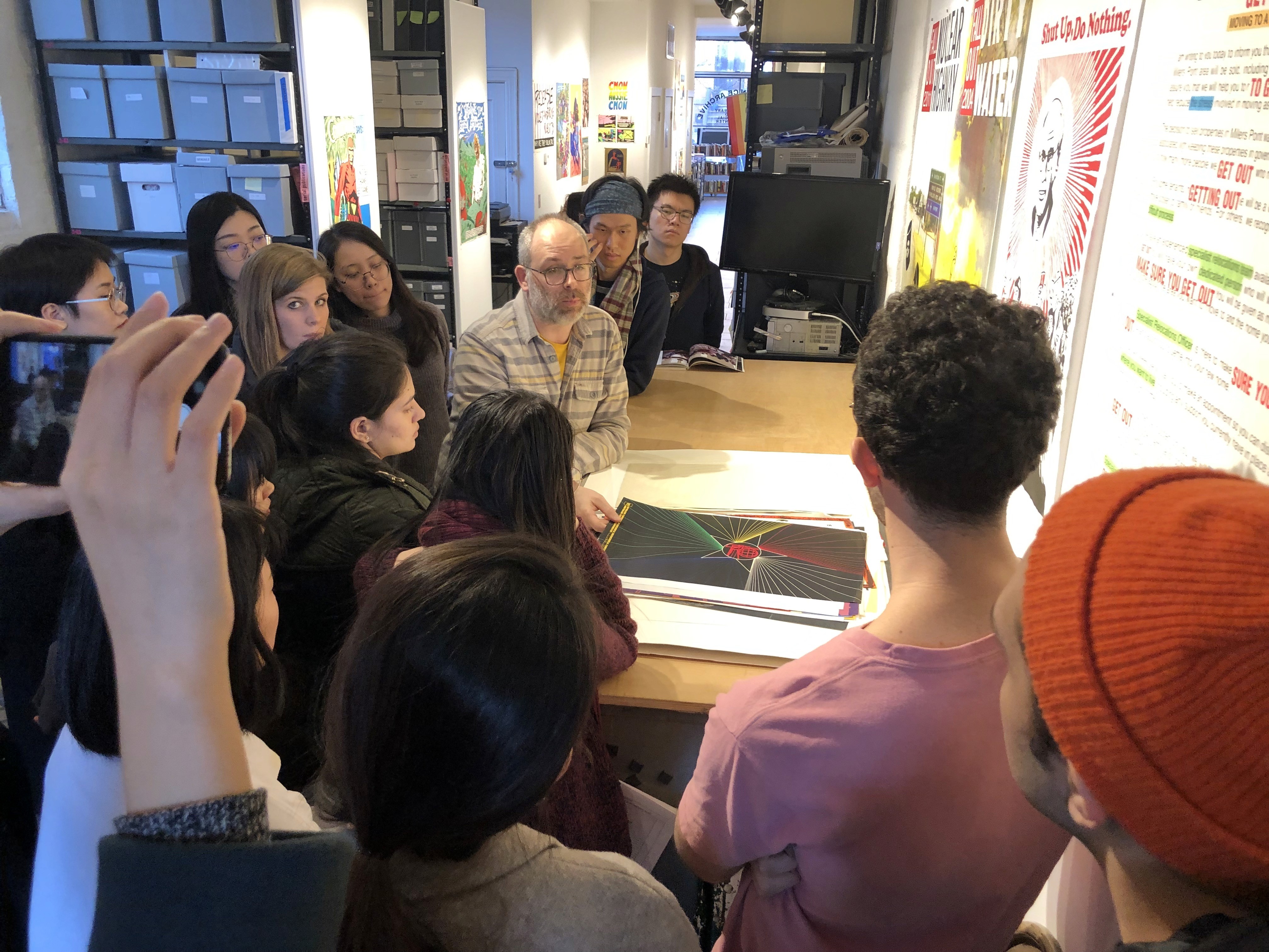 Josh MacPhhee and students looking at poster designs