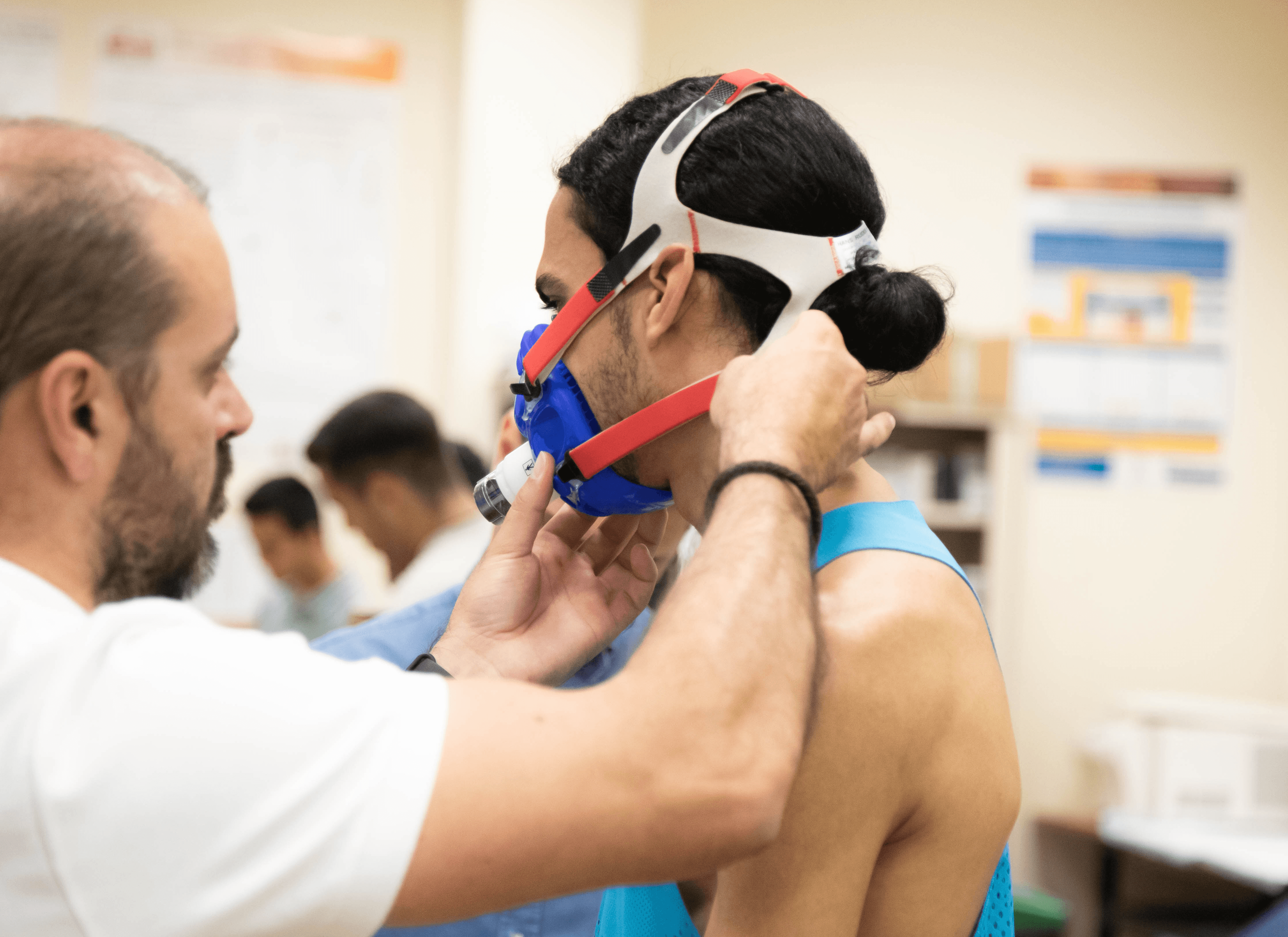 Sports scientist adjusting a metabolic mask on an athlete during a laboratory fitness test