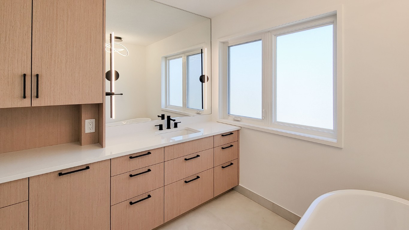 Image of KHD Homes primary ensuite bathroom with modern light wood vanity and large mirror layout design.