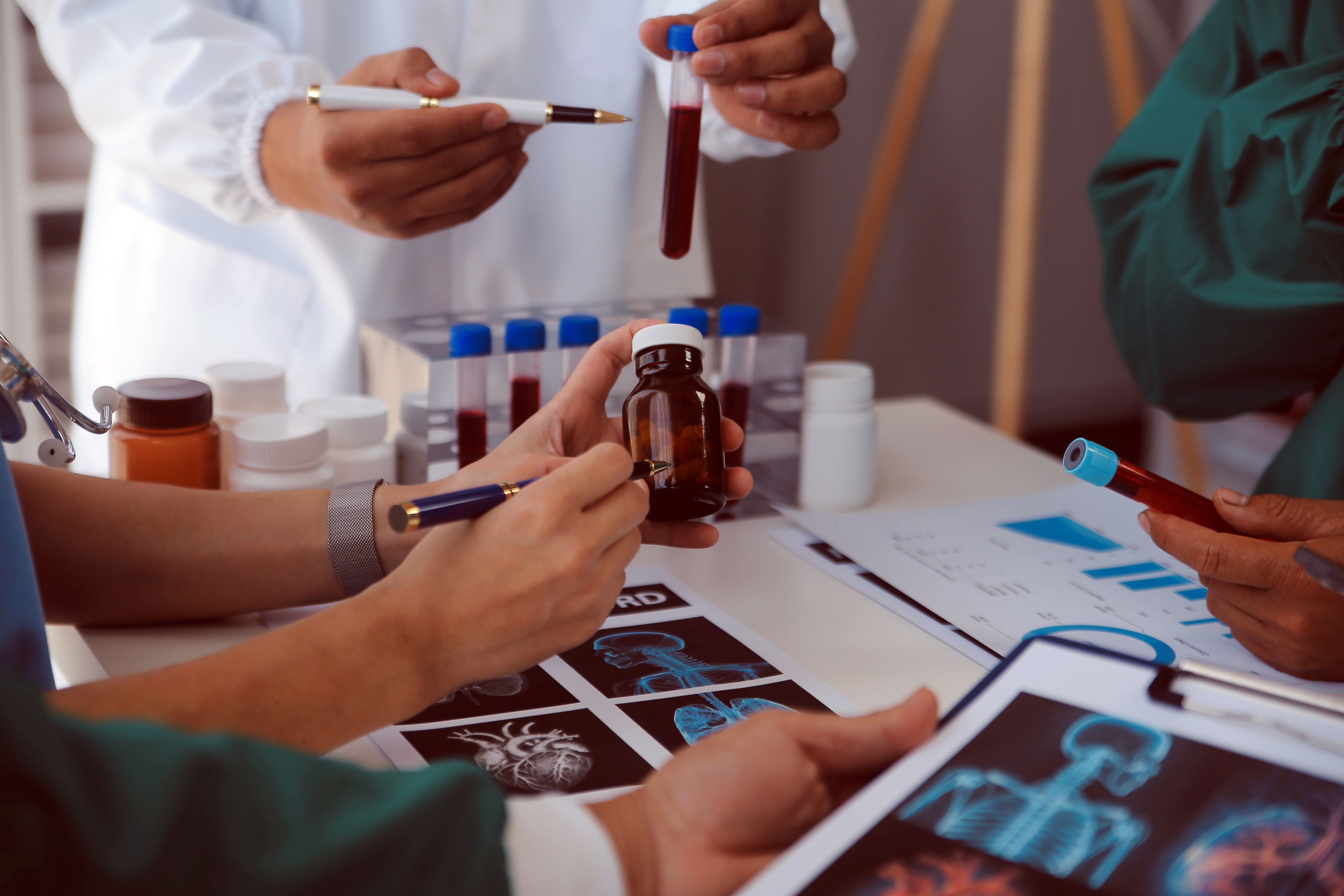 Scientist wearing safety goggles and blue lab attire, using a pipette to transfer liquid into a vial in a laboratory setting.