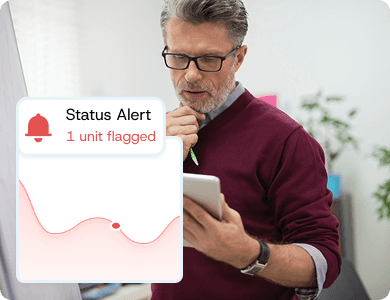 Professional reviewing tablet data with a “Status Alert – 1 unit flagged” notification, representing early detection of underperforming assets.