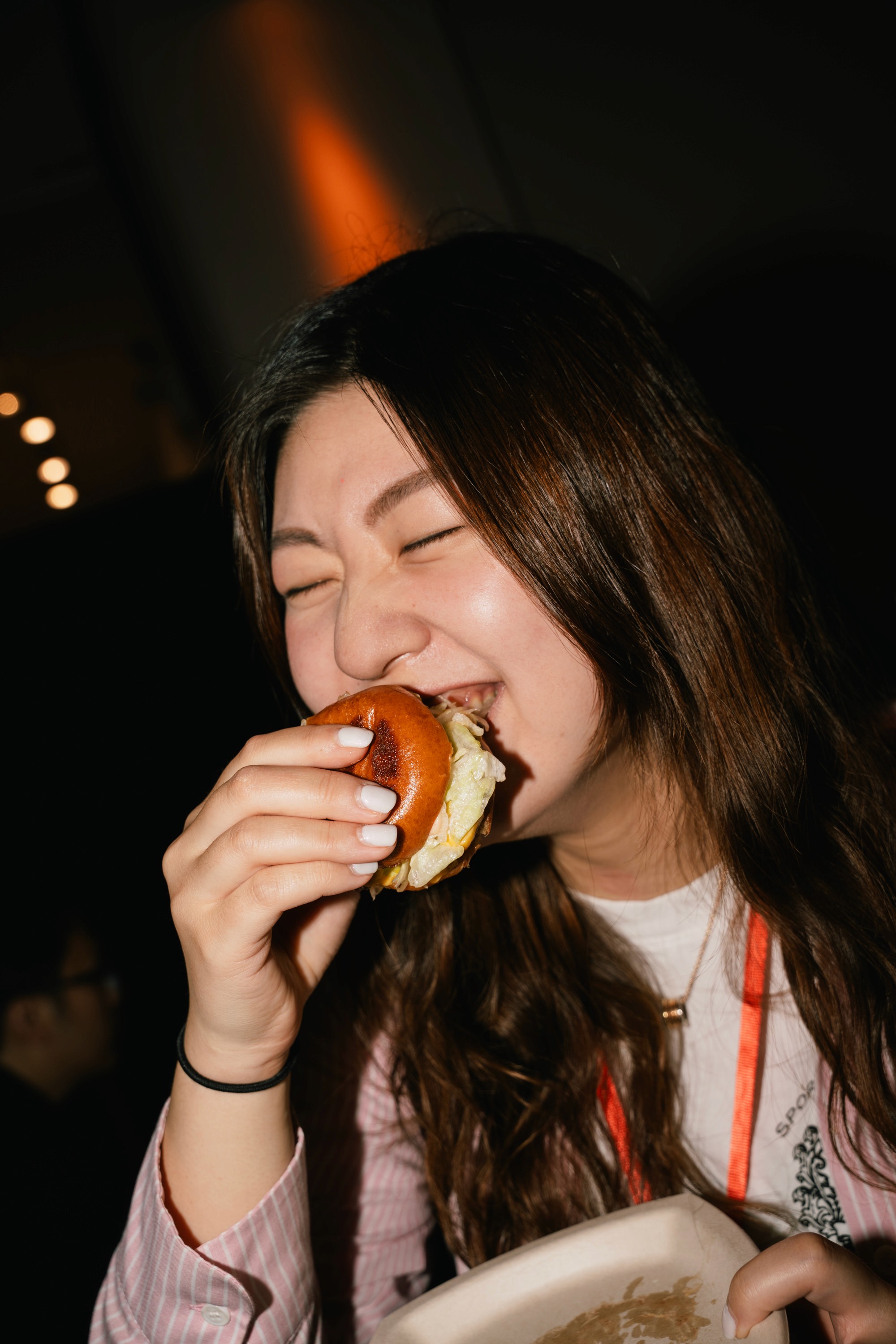 A woman taking a bite of a sandwich with a smile on her face