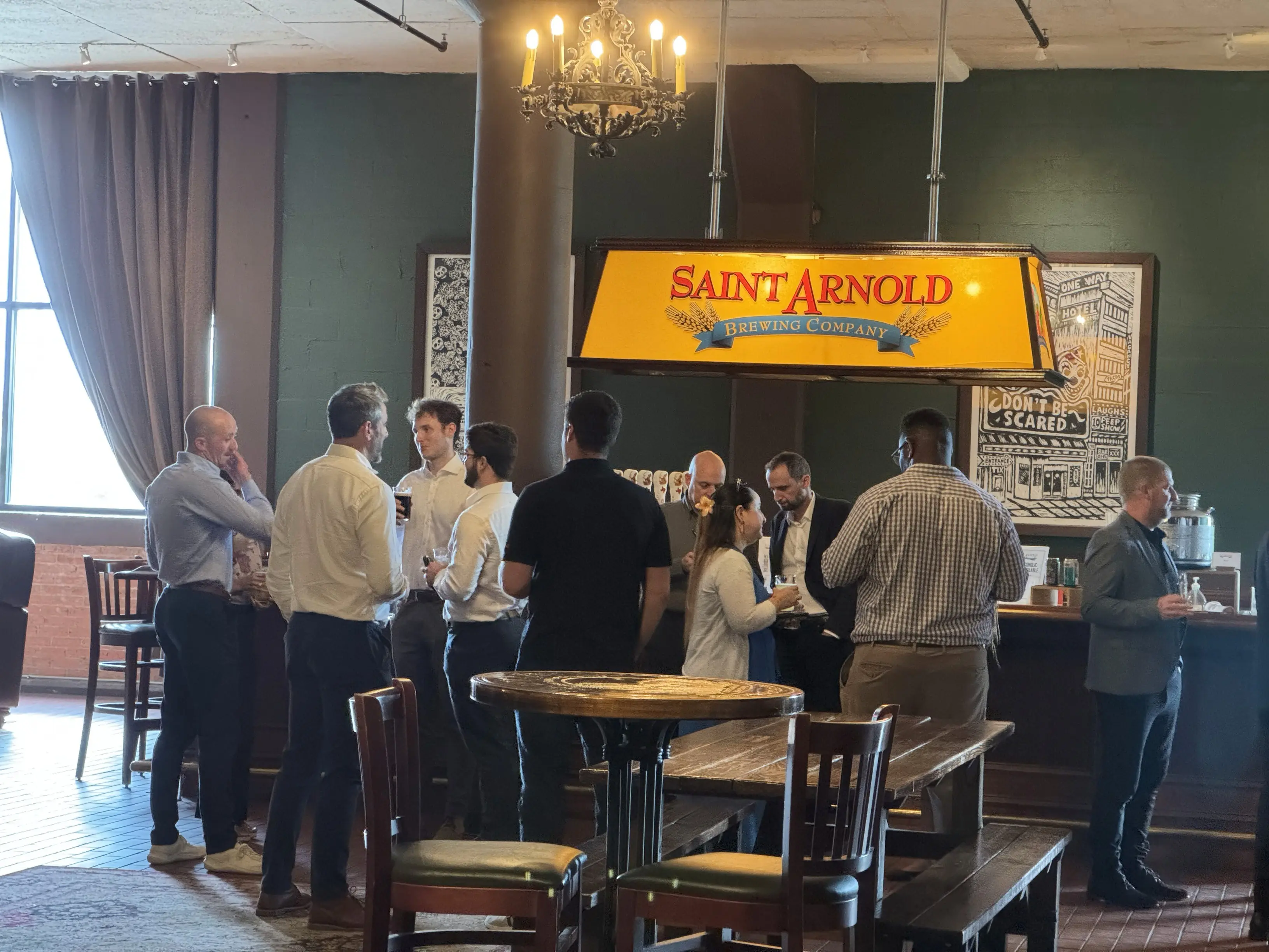 A group of people gathered at a counter in a restaurant or cafe setting, with a banner overhead.
