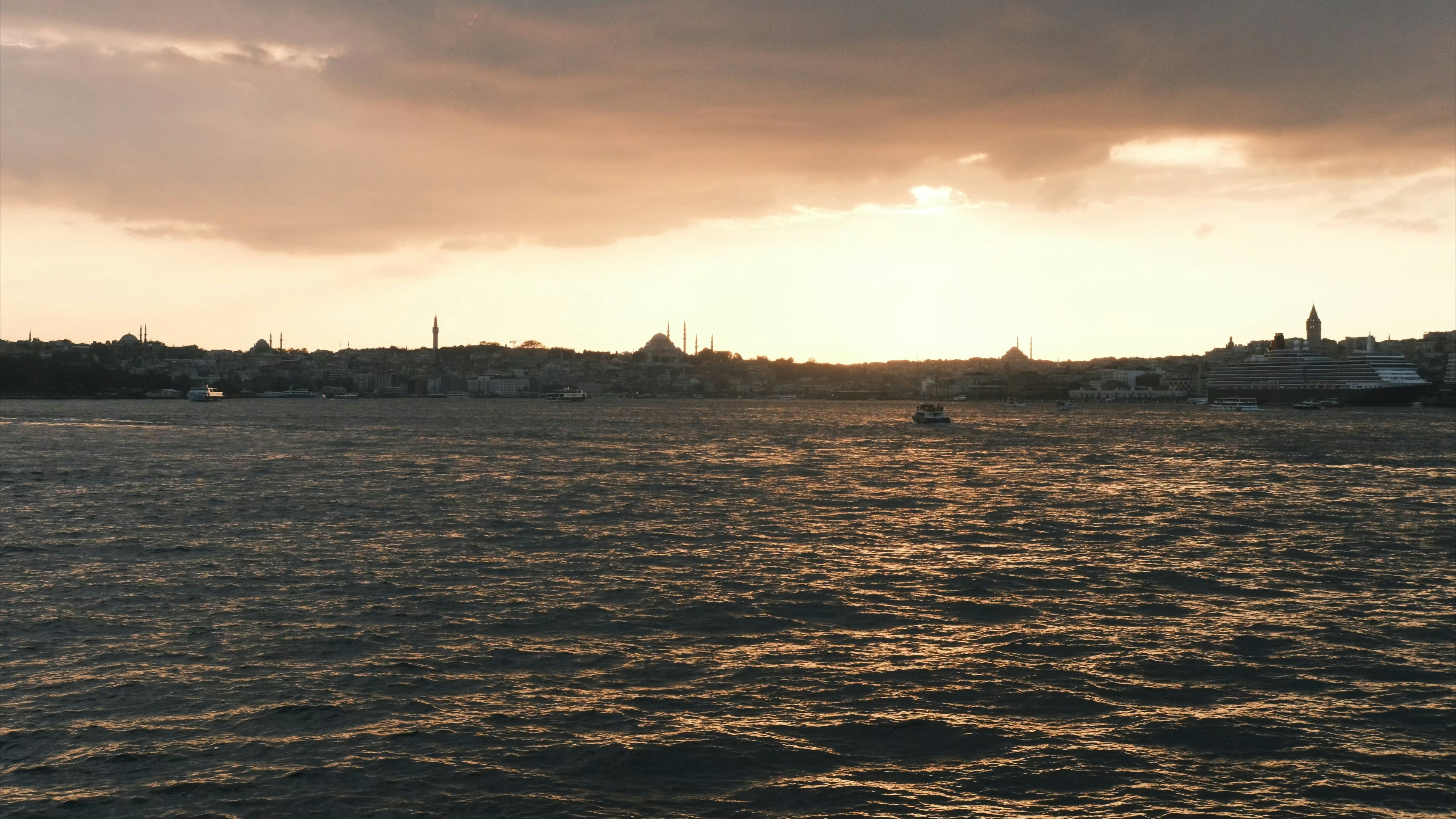 Sunset over a body of water with city skyline.