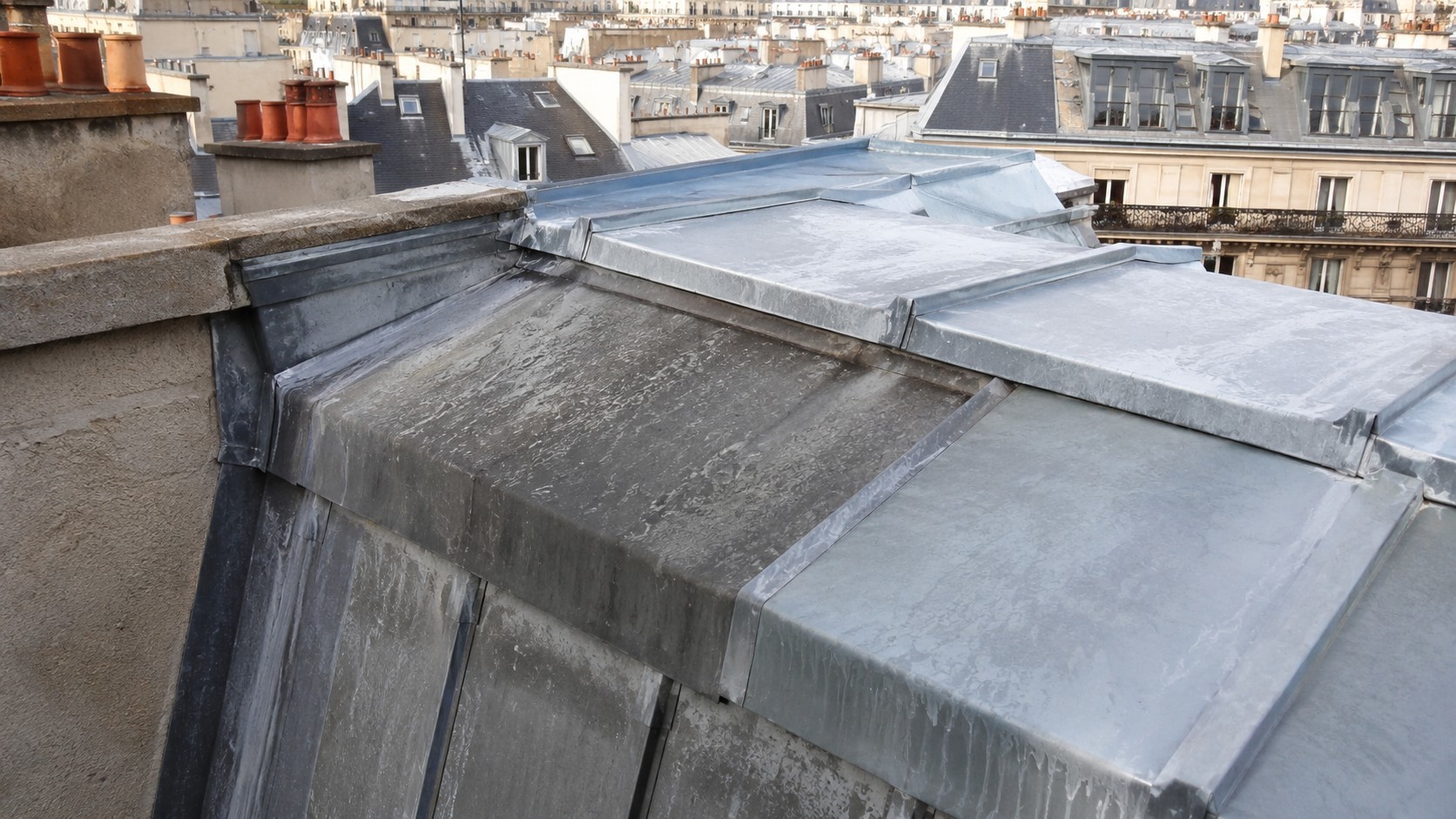 Toiture en zinc à Paris avec patine naturelle, variations de couleur gris bleuté et traces d’oxydation visibles sur les panneaux métalliques