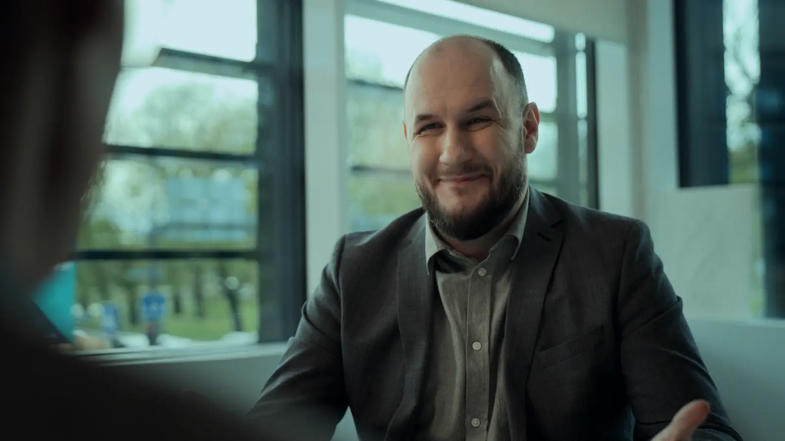Bald man with a beard smiling during a comedy sketch scene
