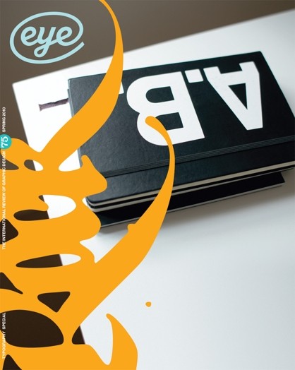 A poster showing a black notebook on a desk with the white letters AB on it.