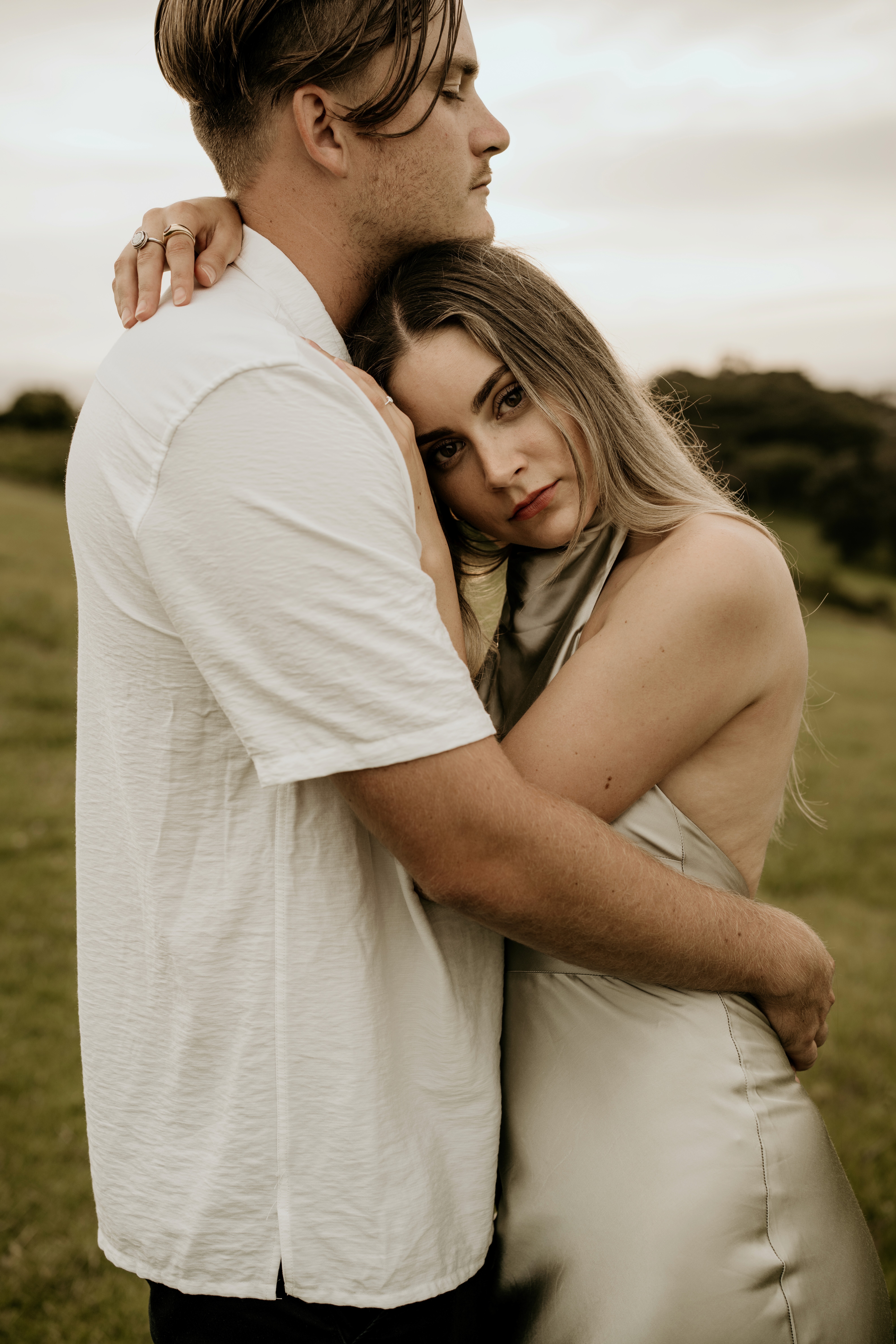 Bride and groom pose by a historic Tudor-style brick cottage with manicured gardens at dusk on the NSW South Coast.