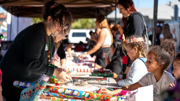Volunteers help kids gift wrap their presents