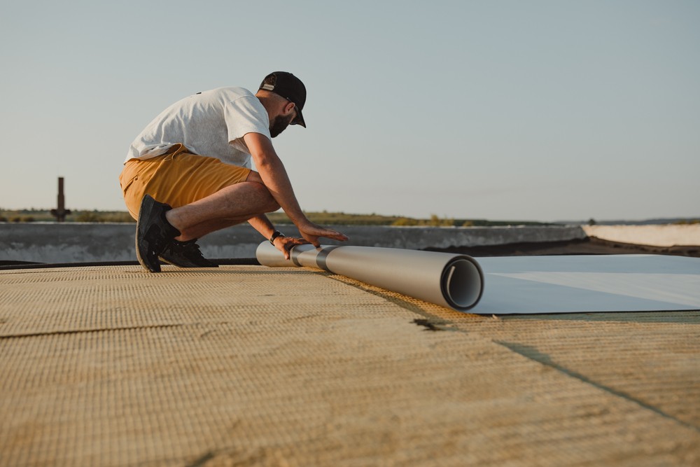 Worker applies pvc membrane roller on roof very carefully