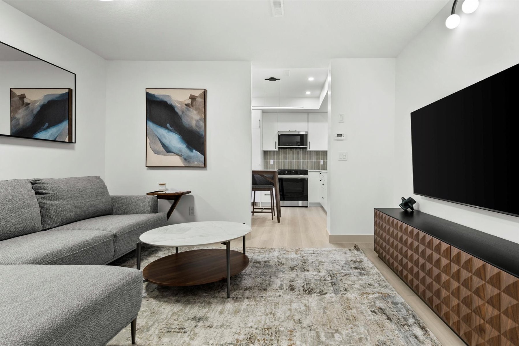 Legal suite living room after: sectional sofa, marble coffee table and the kitchen beyond