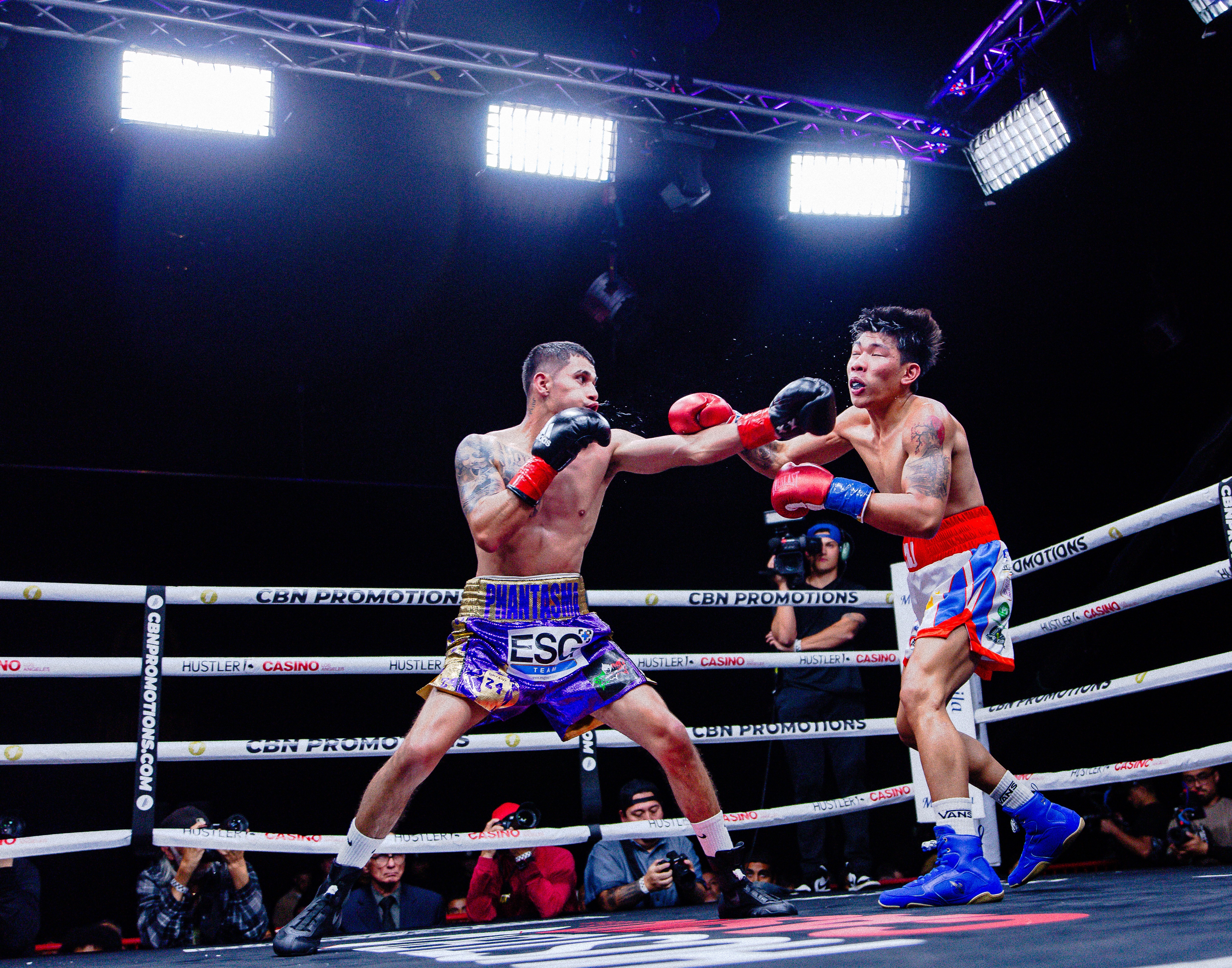 George "El Phantasma" Navarro landing a left hook to the head as sweat flies from the opponent on impact.