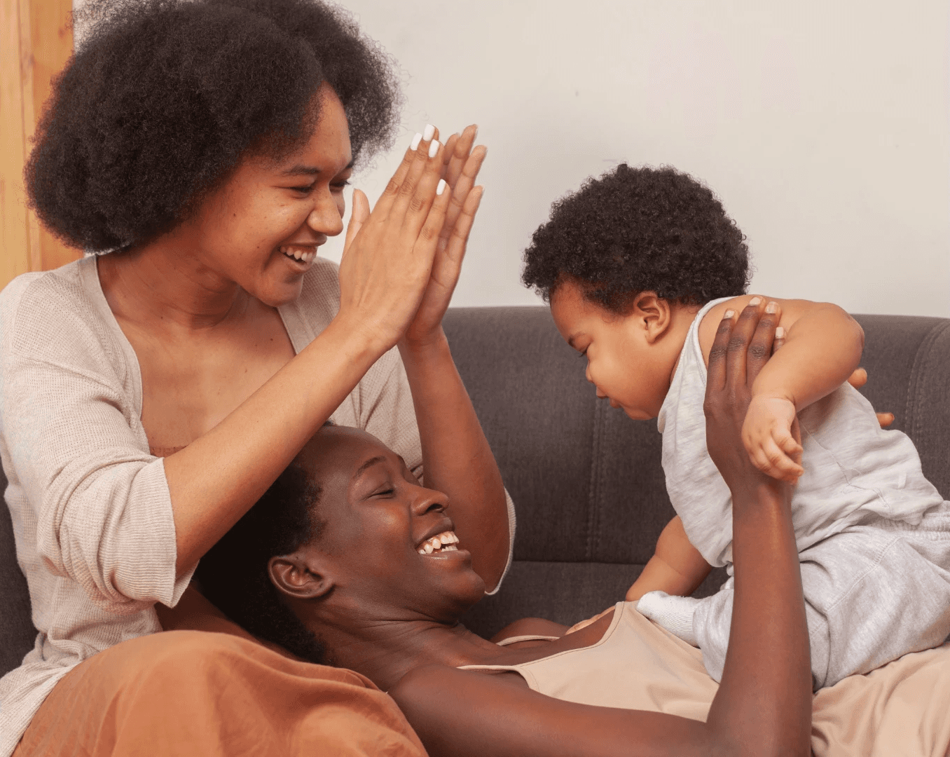 A joyful moment between a parent and child, with laughter and playful interaction on a cozy couch.