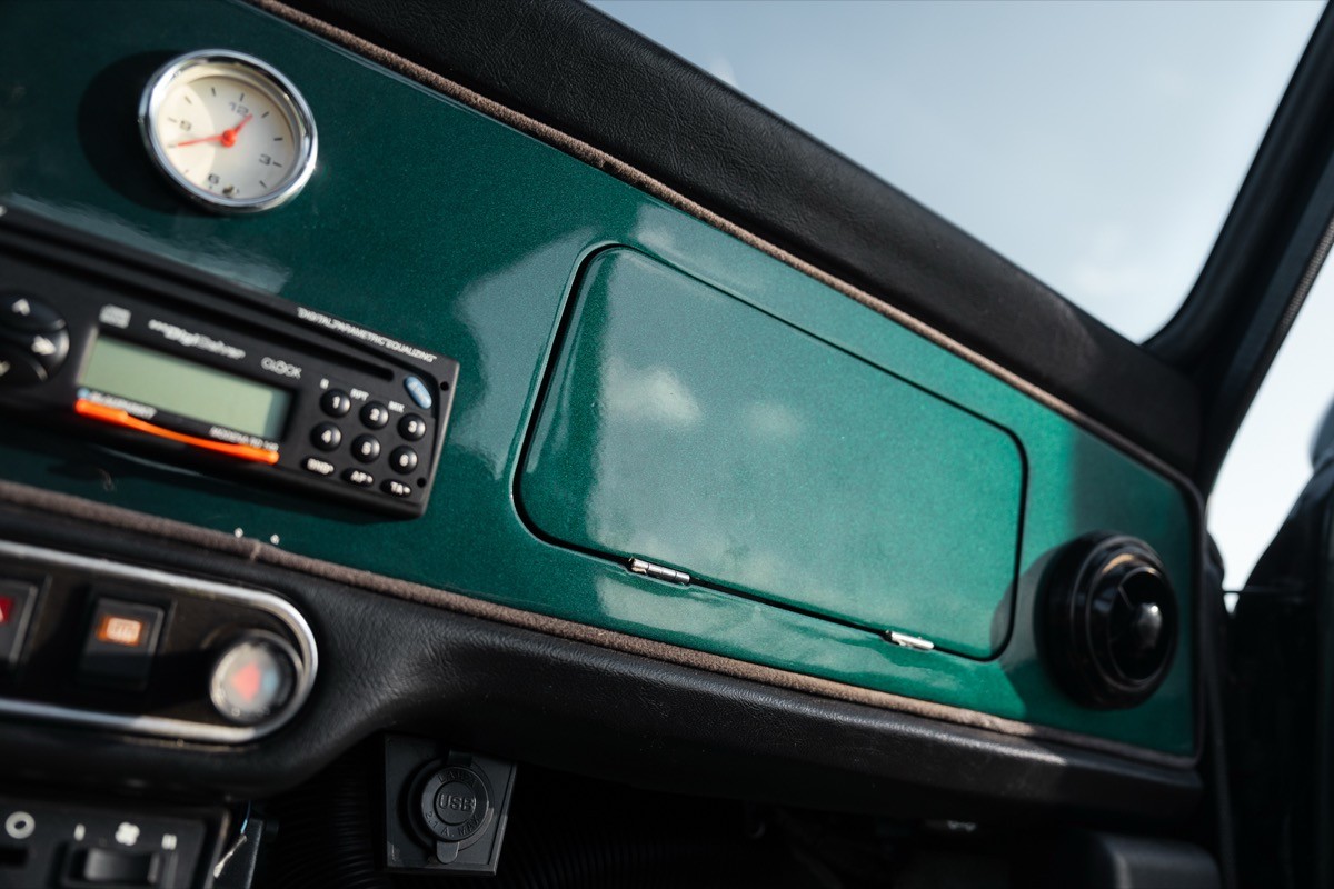 Close-up of a car dashboard featuring a green panel, radio controls, and a speedometer.