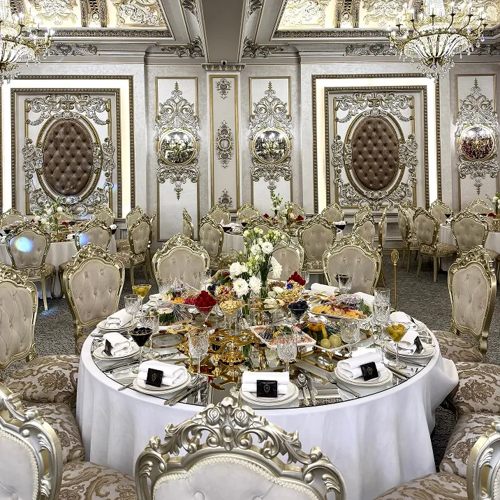 Elegant banquet hall with gold decor, floral centerpiece, and formal table setting