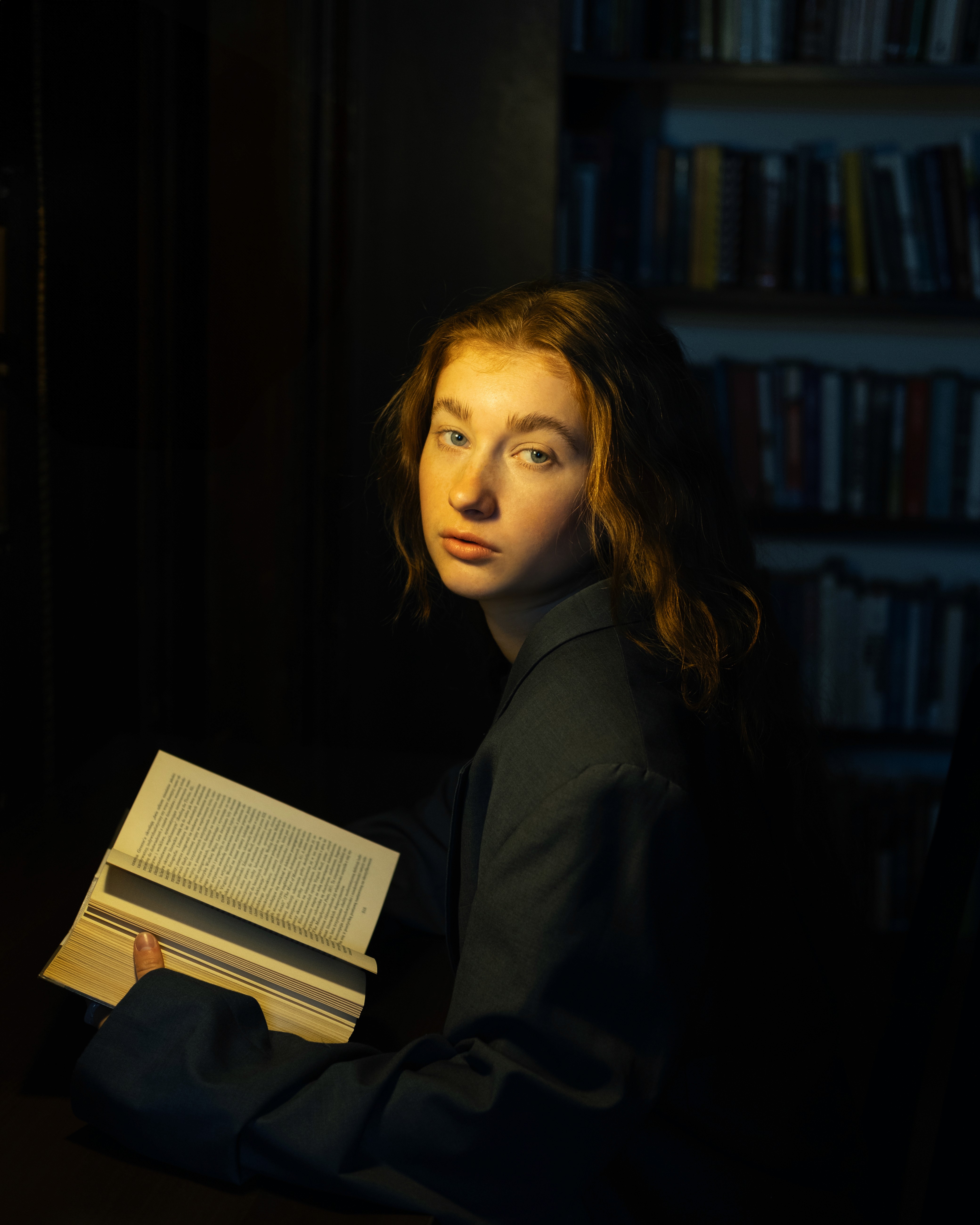 Elizabeth – Night Reader - studying among bookshelves in low light.