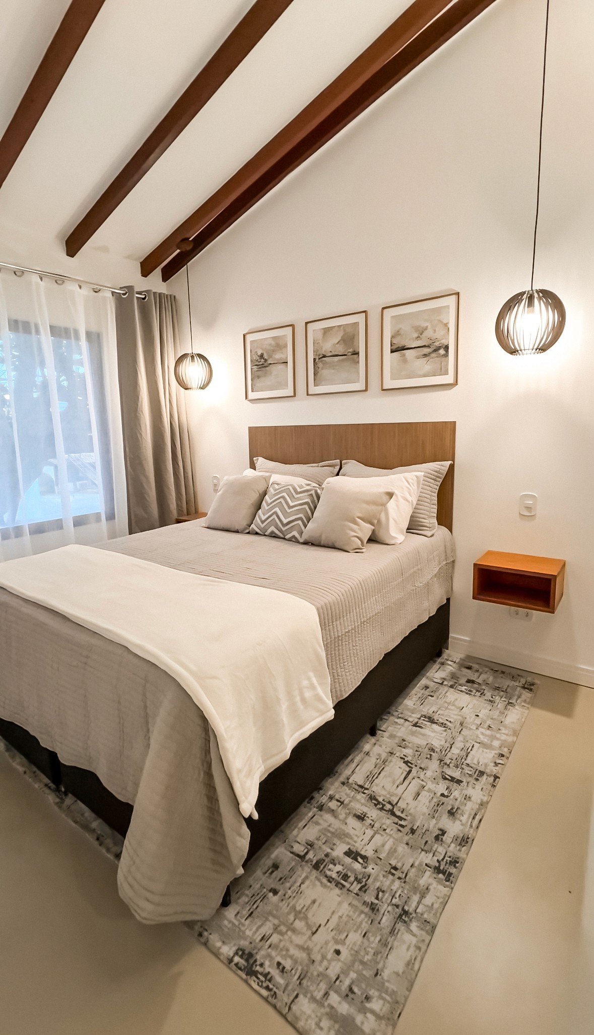 spacious open-plan suite with king bed, sofa lounge, light wood flooring, and ocean views through sliding glass doors.