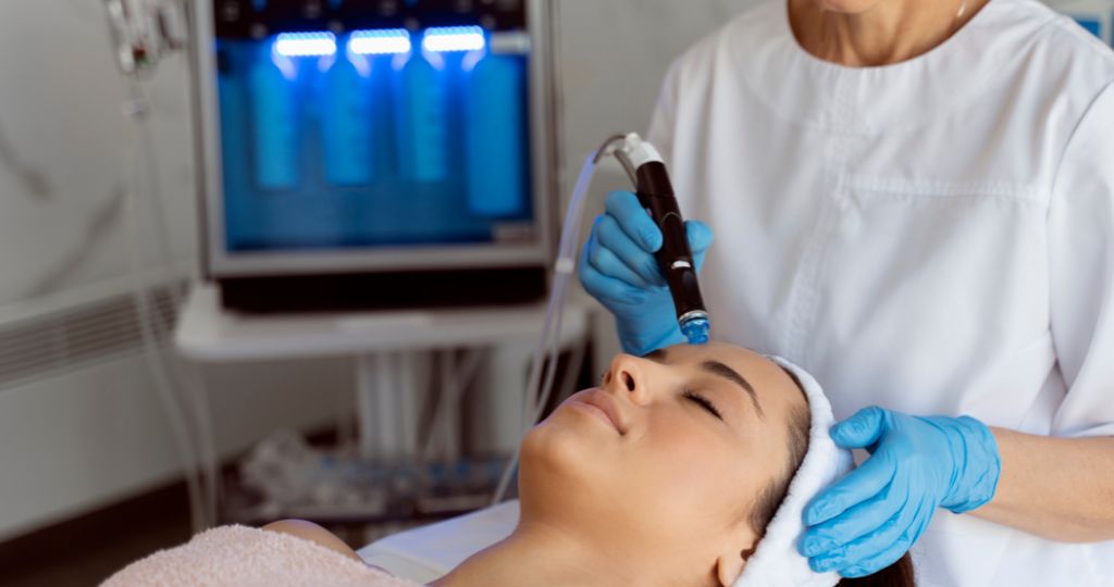 Laser cosmetic clinic staff performing facial treatment with advanced equipment