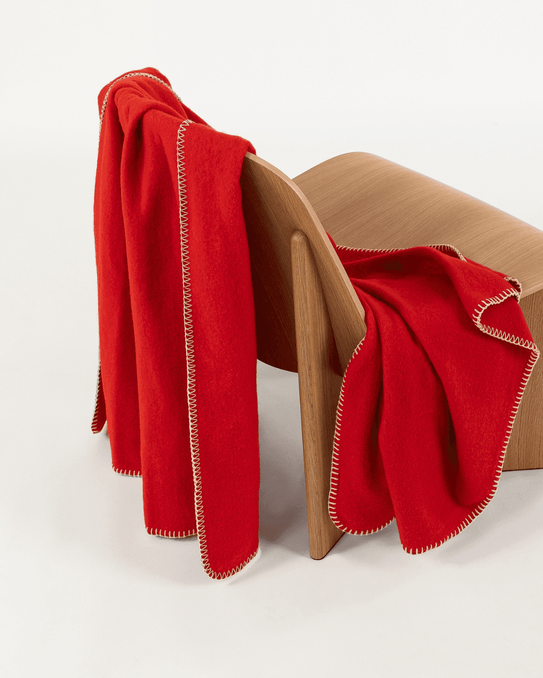 Merino wool blanket in poppy draped over a wooden chair