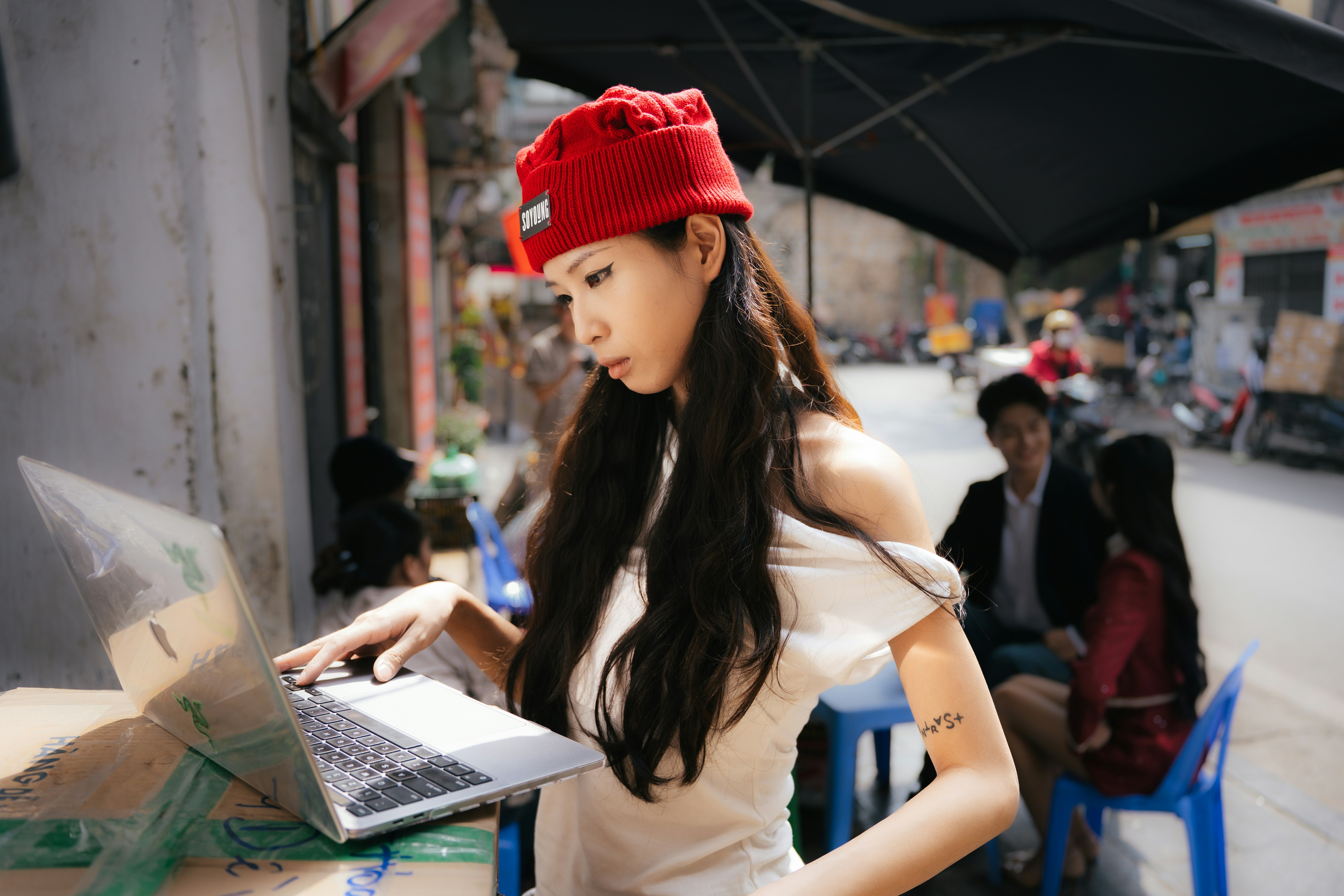 Young woman in red hat using laptop outdoors
