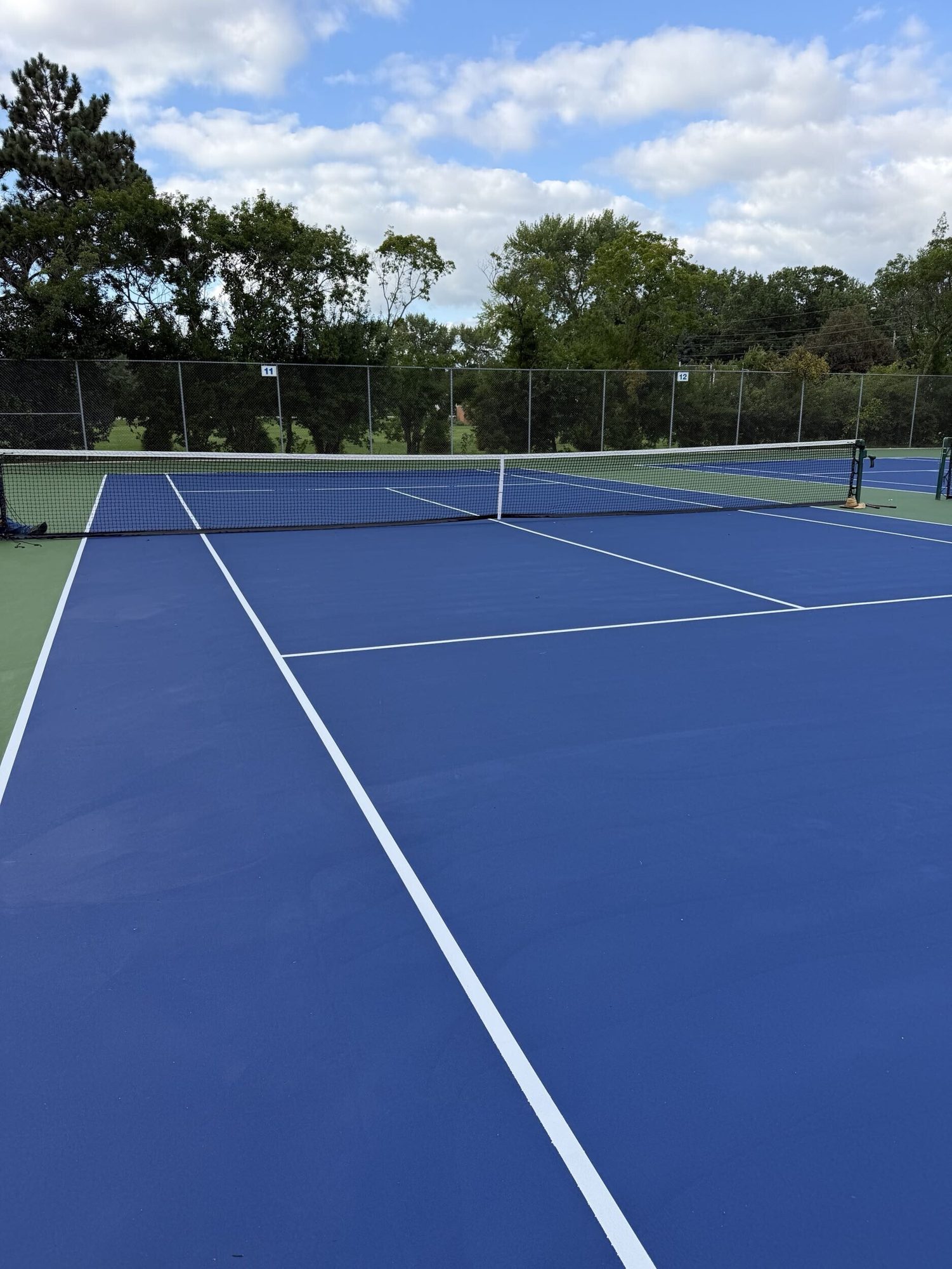 Resurfaced tennis court viewed from the baseline at Byrnes Tennis Center in Waterloo, IA