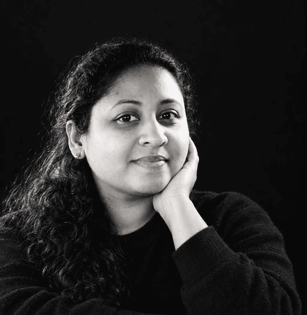 Smiling blonde woman with freckles in a white shirt, arms crossed, minimalist studio portrait.
