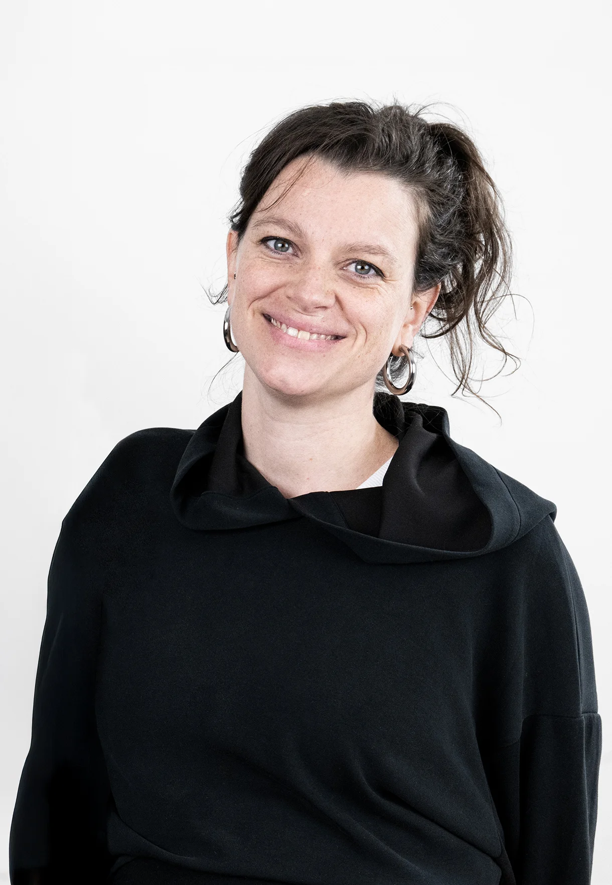 A circle of people sitting cross-legged, meditating with hands in a prayer position. Soft, warm lighting.