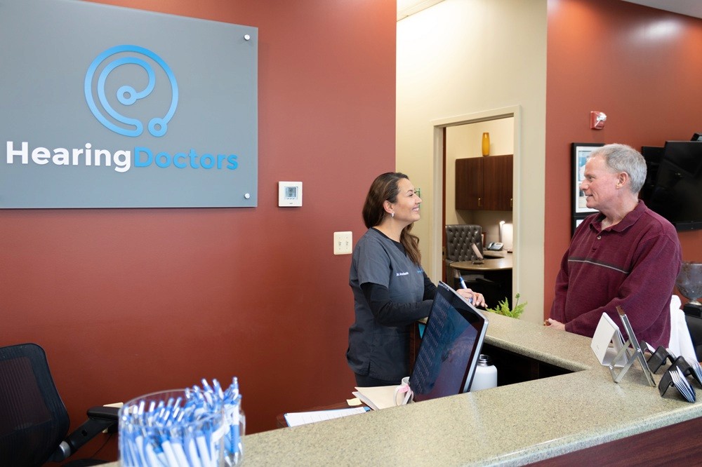 Two individuals sitting on a modern sectional sofa in a bright, minimalist room, engaging in conversation.
