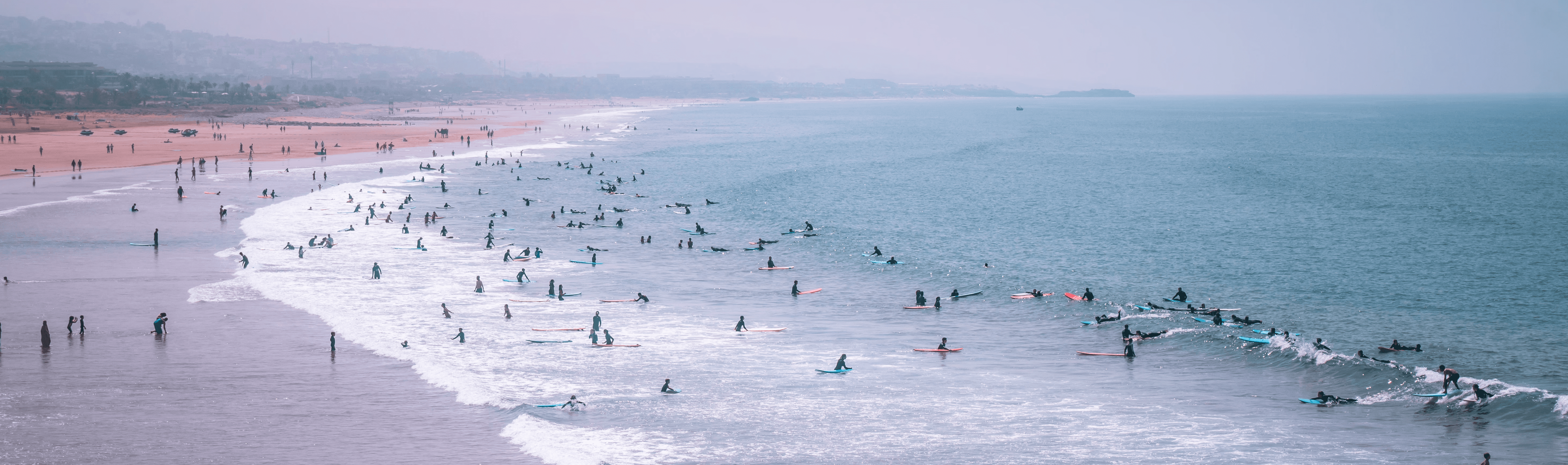 A busy surf lineup and beach along the coast near Taghazout on an ordinary day
