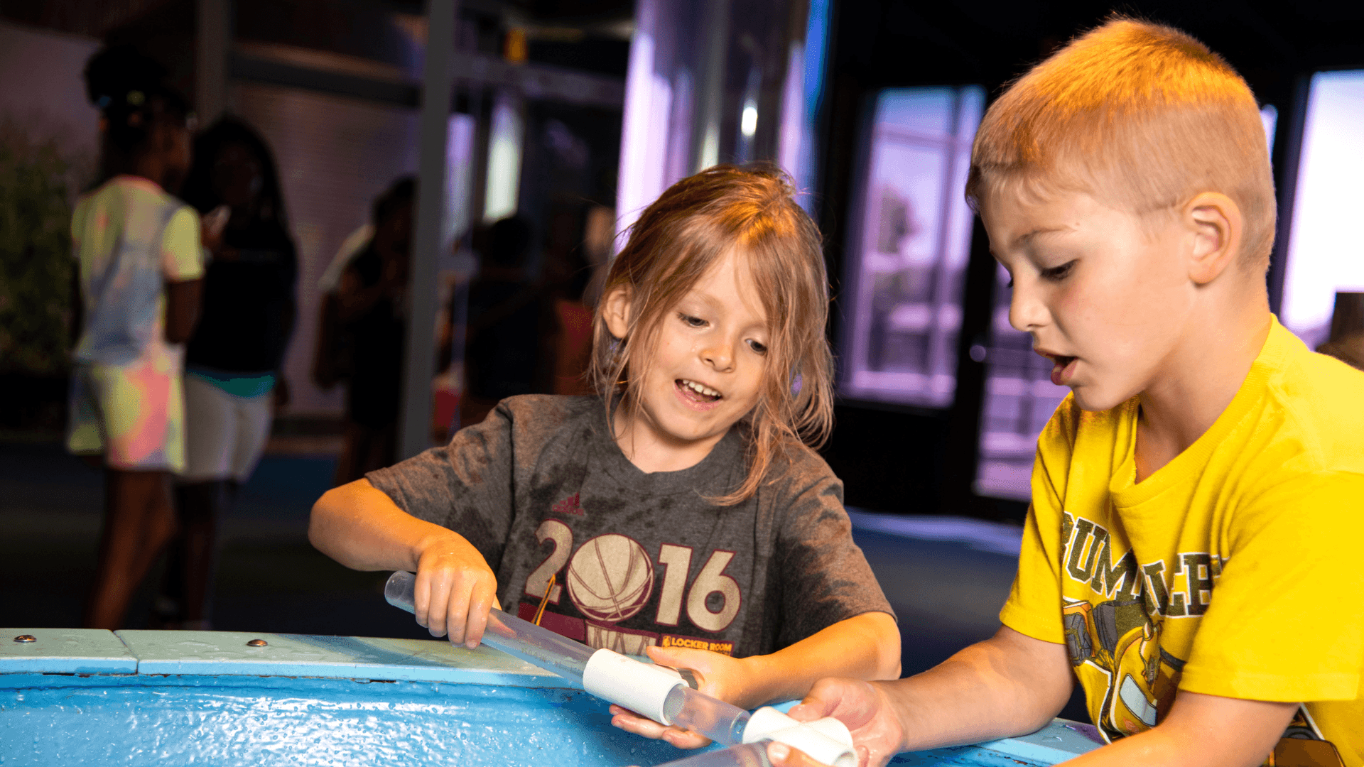 A young boy and girl work together to put together pieces in the water table.
