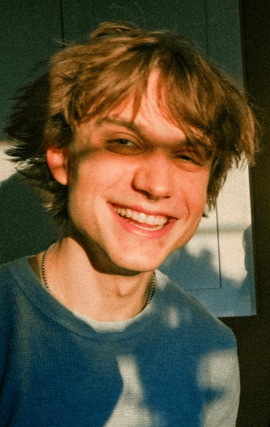 A thoughtful young person with dark hair gazes to the side, captured in soft black and white lighting.