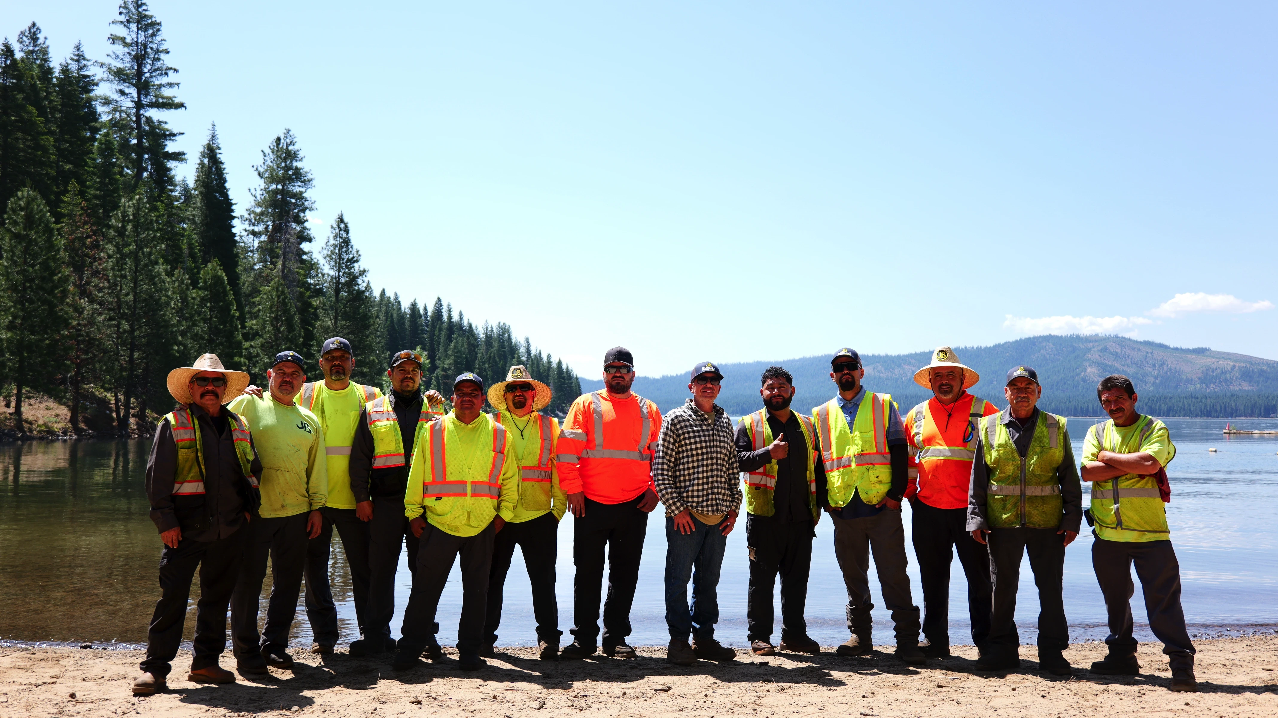 Asphalt paving crew pose for group photo in front of alpine lake