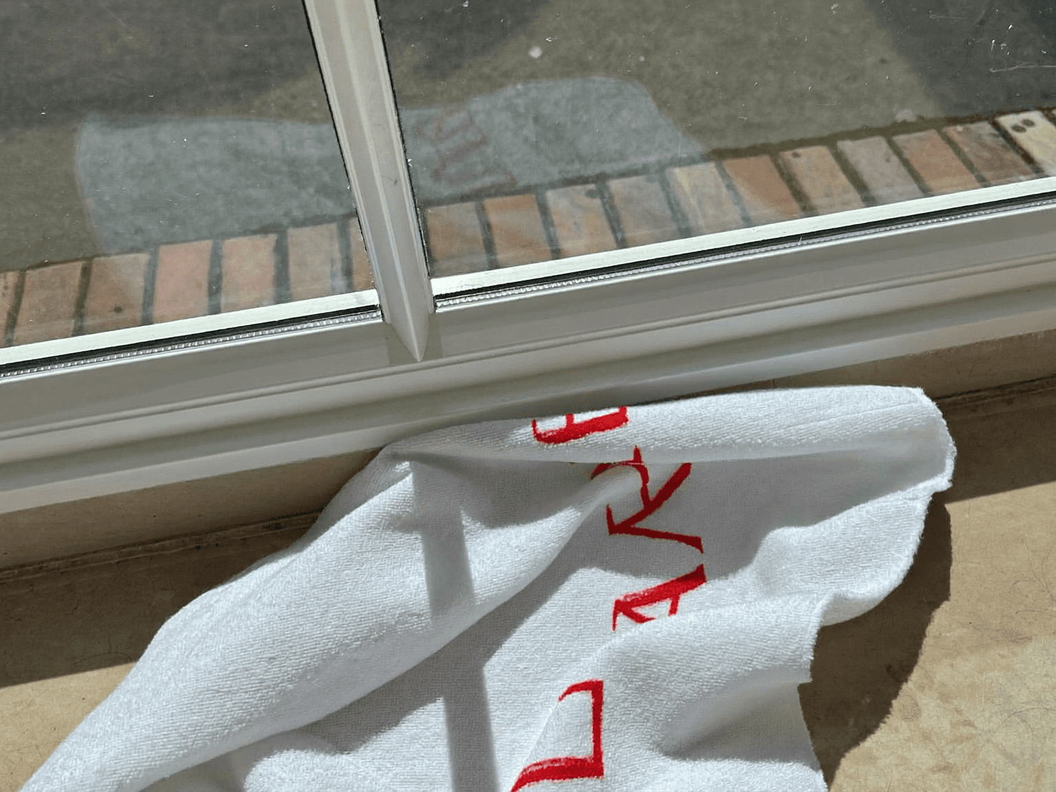 Branded microfiber towel resting on a freshly cleaned window sill track