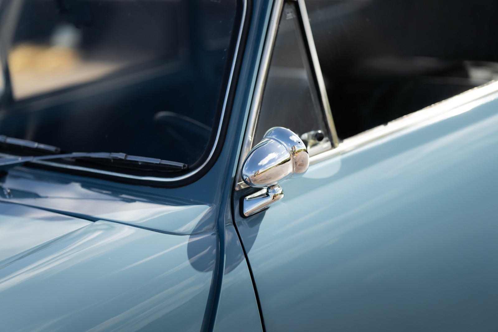 Close-up of a classic car's door handle in light blue paint, showing reflections and details.