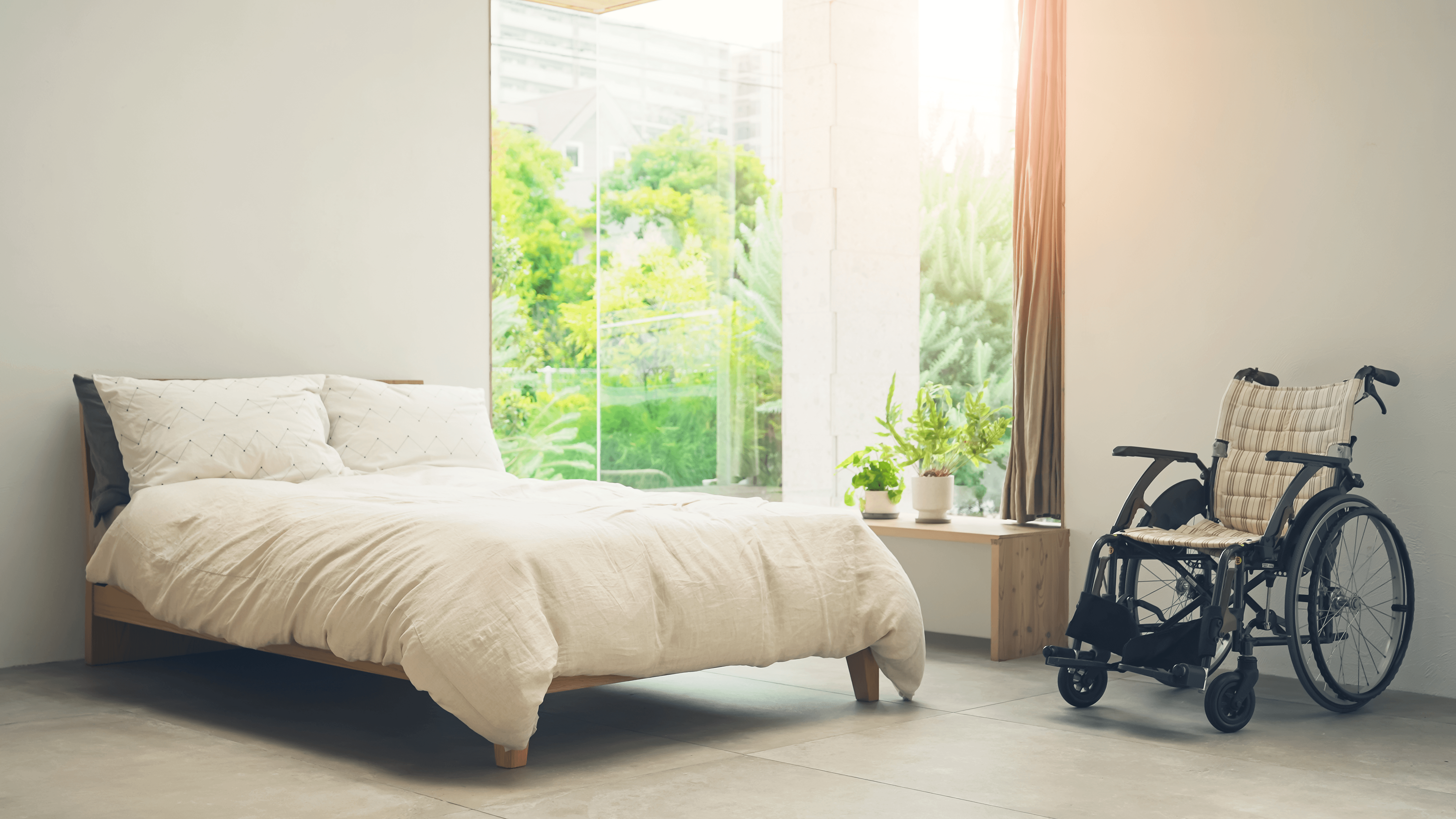 A bright bedroom with a wheelchair beside the bed.