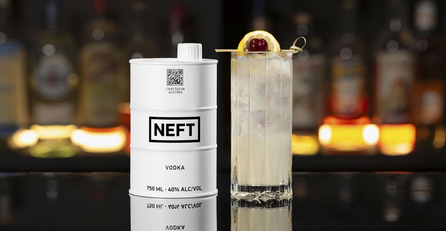 A NEFT Barrel and a glass of Vodka Collins on a bar counter.